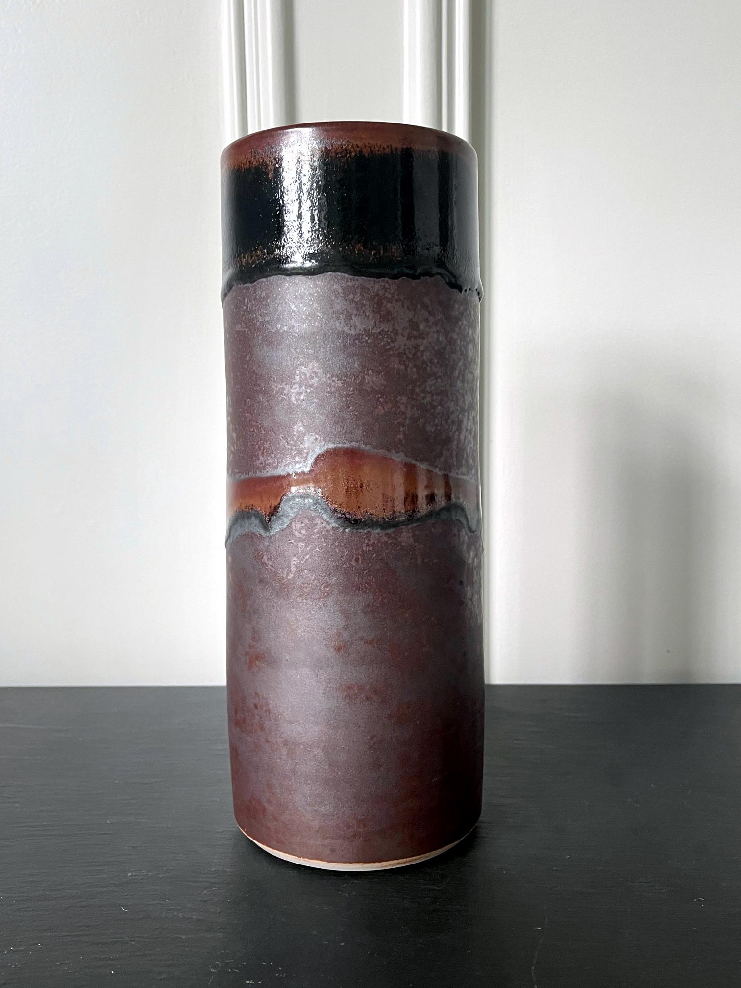 Vase en céramique de forme cylindrique légèrement effilée, réalisé par le potier Frère Thomas Bezanson (1929-2007). La silouette minimaliste est étonnamment primordiale avec son bord de bouche plus large dans le cercle parfait, rappelant la forme de