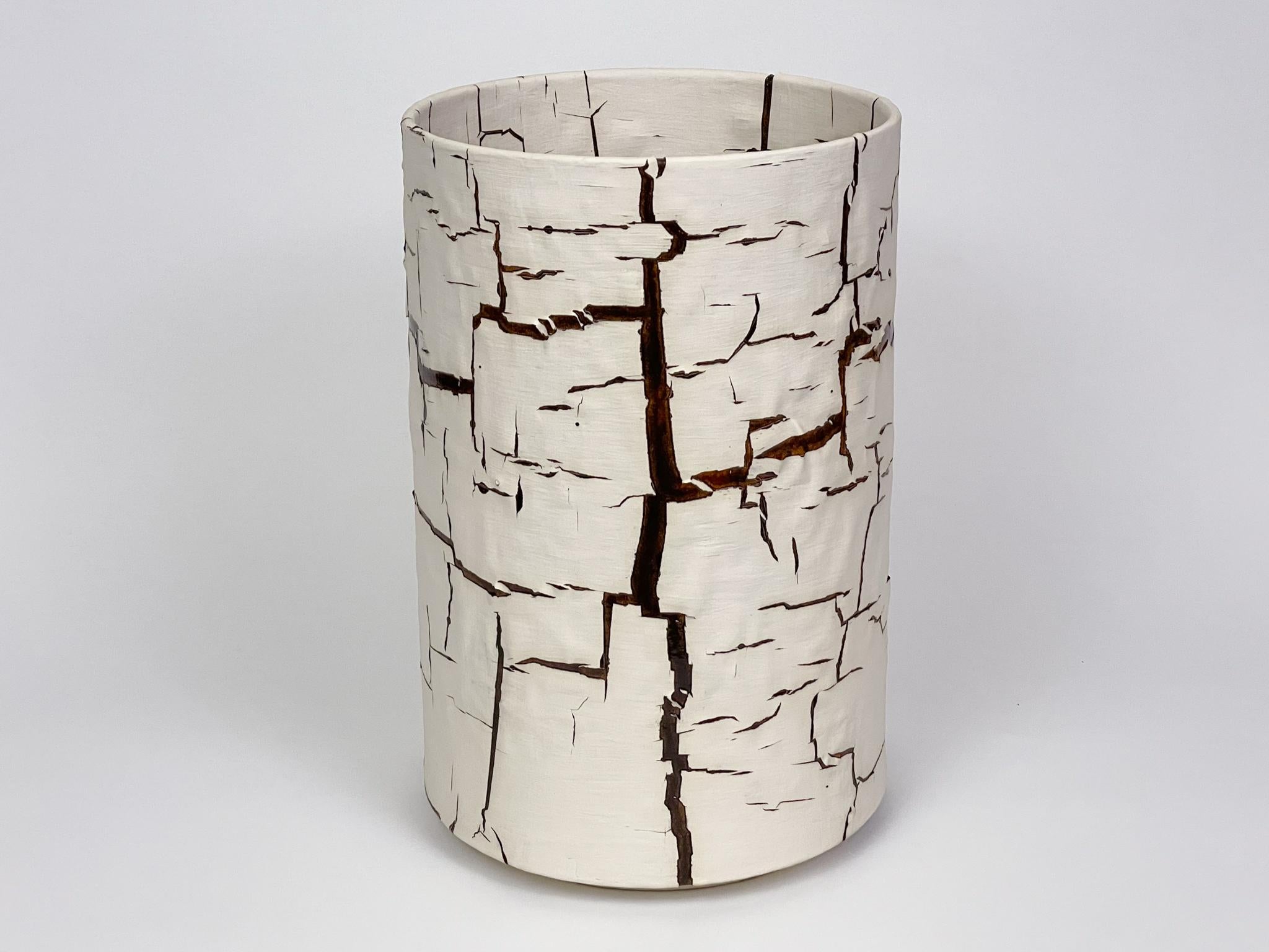 Glazed ceramic cylindrical sculpture by William Edwards
Hand built earthenware decorative vessel, fired multiple times to achieve a textured surface of random abstraction, White matte with dark amber gloss glaze breaking through.

William received