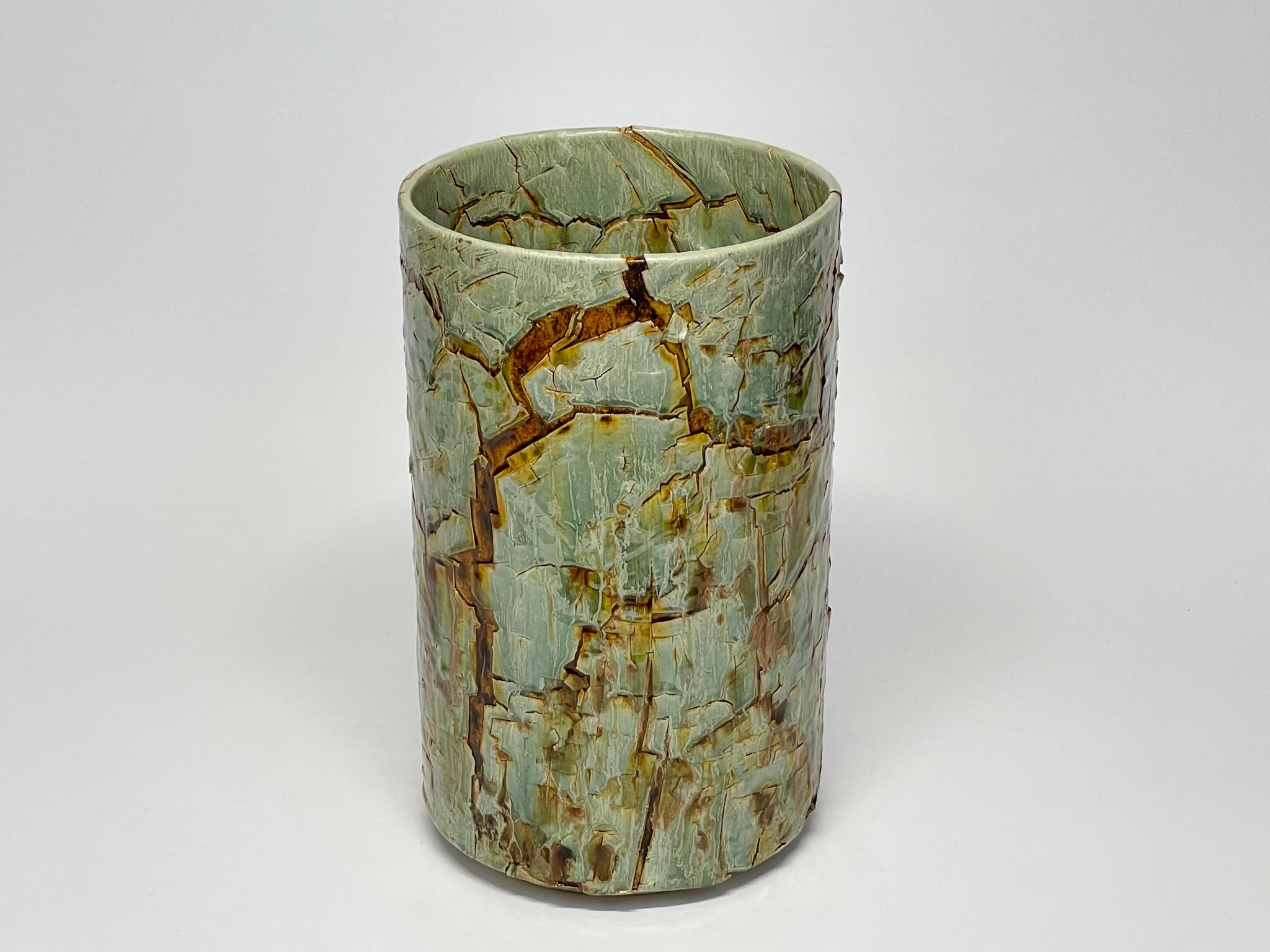 Glazed ceramic cylindrical sculpture by William Edwards
Hand built earthenware decorative vessel, fired multiple times to achieve a textured surface of random abstraction, in hues of celadon green with amber gloss glaze breaking through. and