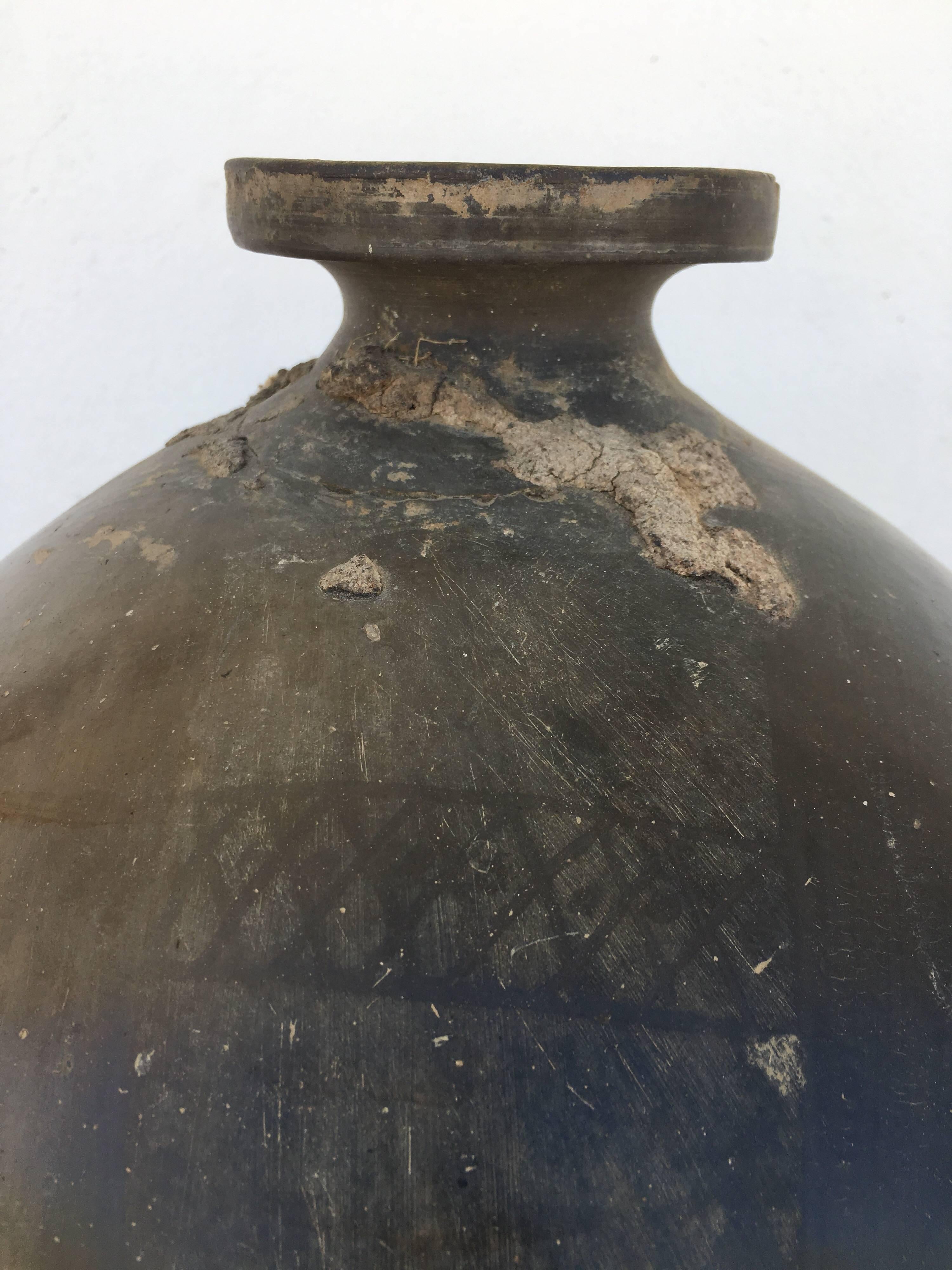 Black clay teardrop ceramic clay jug from the 1950s. Visible original markings by artisan the most important being a drawing of a flower and leaves. The neck was repaired at one point by the mezcal producer that purchased this container as a means