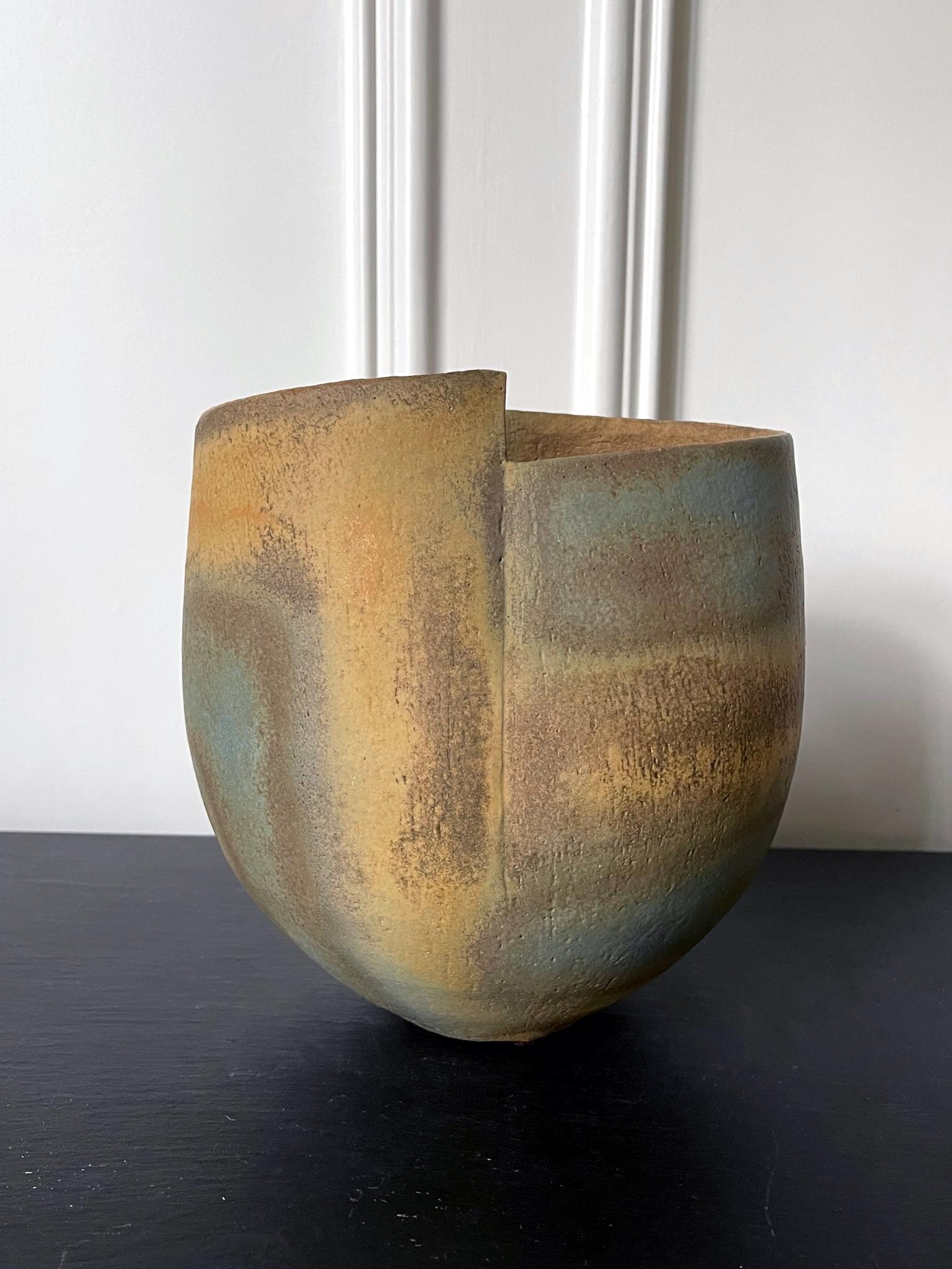 Un récipient en grès avec un design de bandes émaillées et bandées par le céramiste de studio britannique John Ward (1938-2023) vers les années 1980. Le récipient prend sa forme simple mais distincte entre un bol profond et un vase. Il présente un