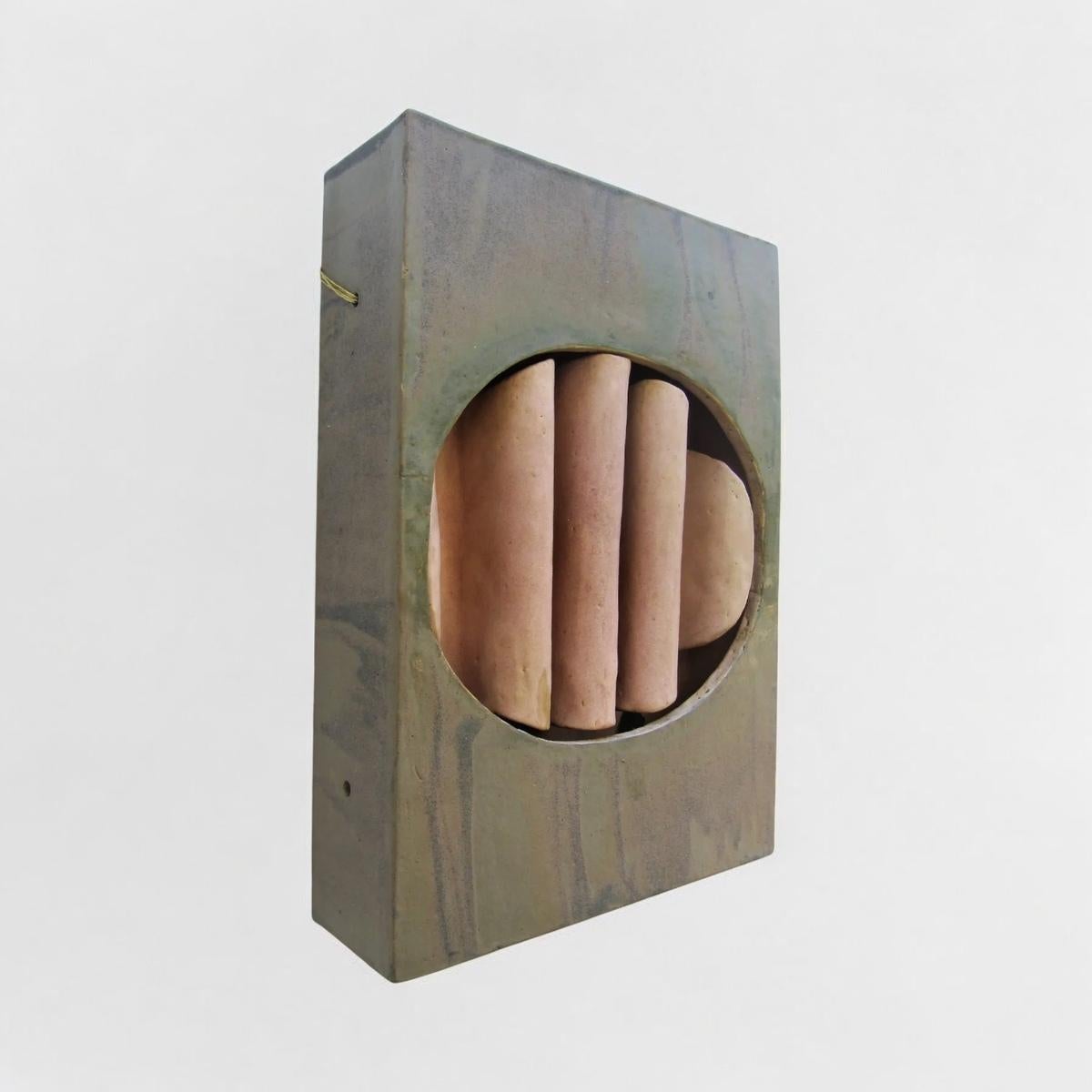 This ceramic wall light, created around 1975 by German artist Walburga Kulz (b. 1931), exemplifies her blend of sculptural design and functional utility. Featuring a rectangular structure with an oval cut-out framing vertical ceramic elements, the