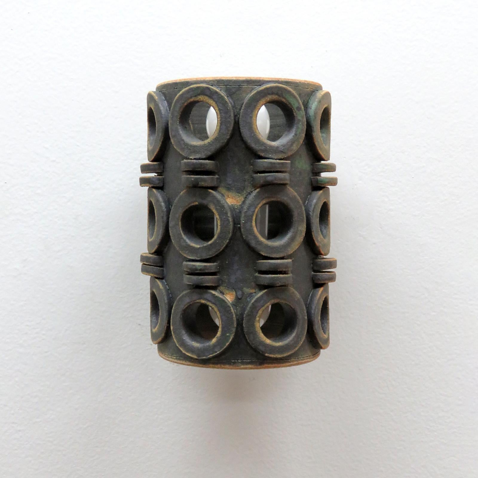 wonderfully sculptural ceramic wall light No.49/2, designed and handcrafted by Los Angeles based ceramicist Heather Levine. High fired stoneware with matte burnt olive glaze body with decorative perforations to expose light in patterns on nearby