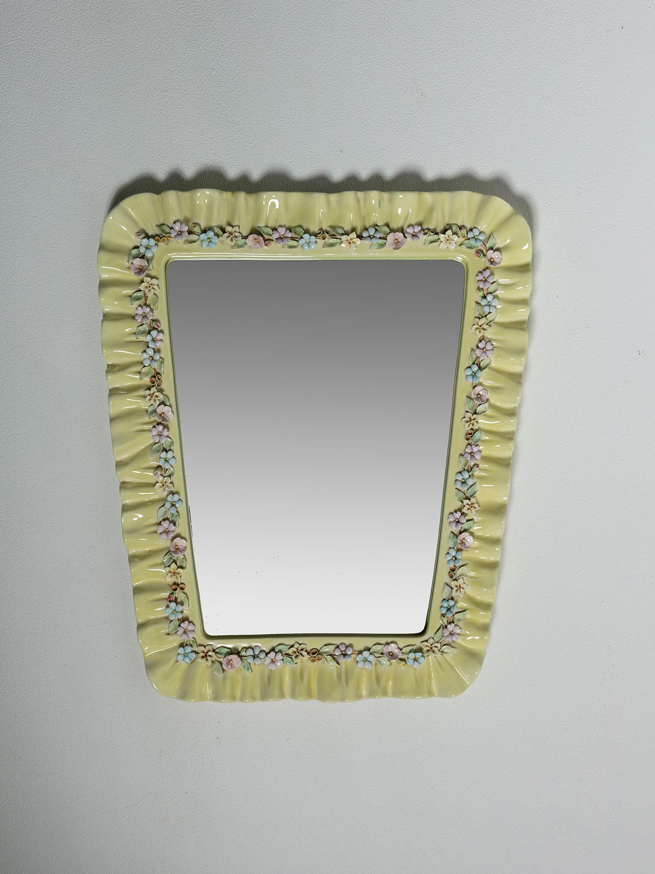 Thin ceramic frame decorated with flowers composes this wall mirror, attributed to Lenci manufacturer.
