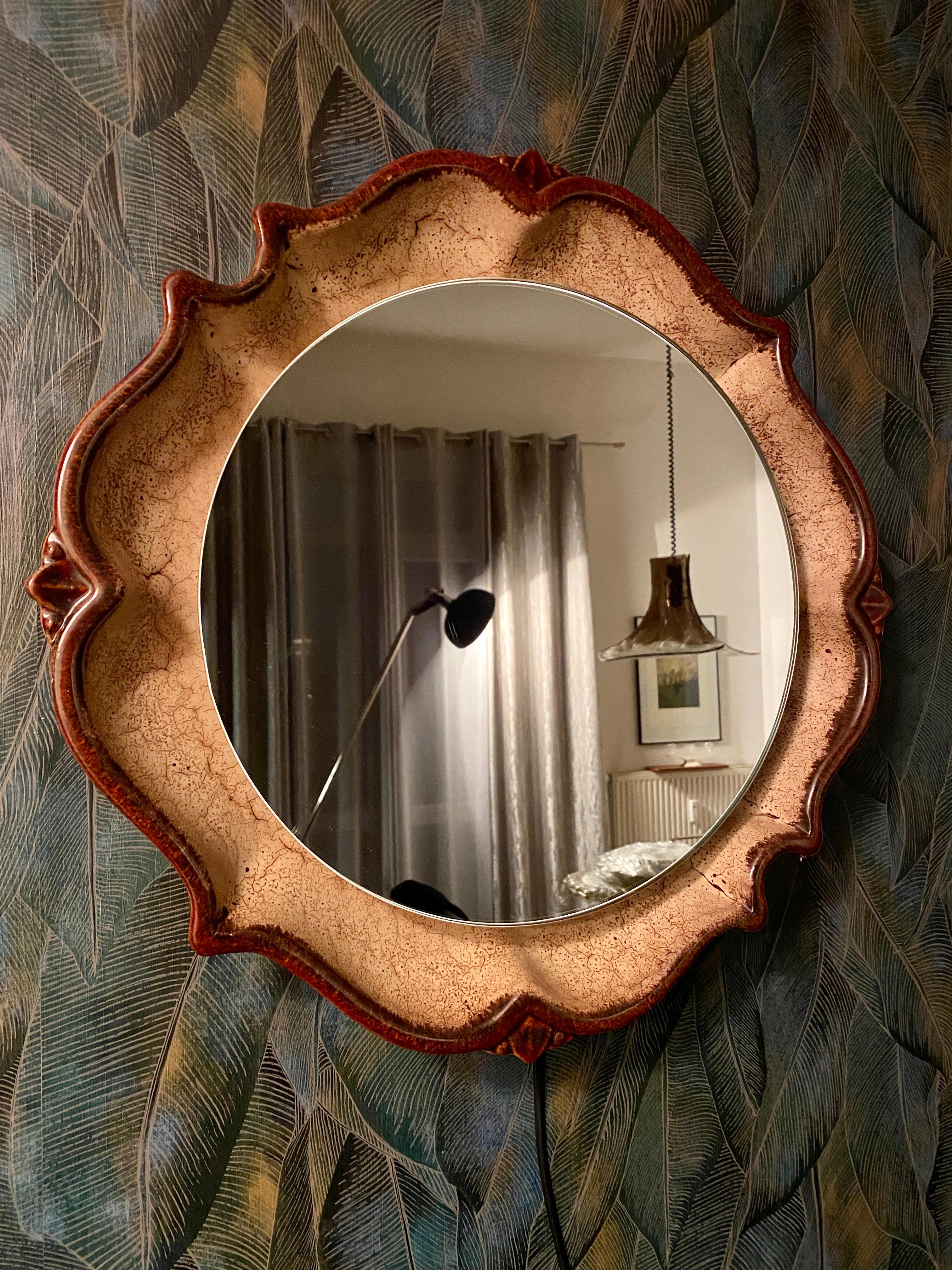 A ceramic wall mirror with indirect lighting from the German manufacturer PAN. It was manufactured in the 1960s.

The frame accommodates three E14 light bulbs (max. 40W). The mirror frame is made of ceramic, and the frame is made of metal.
This