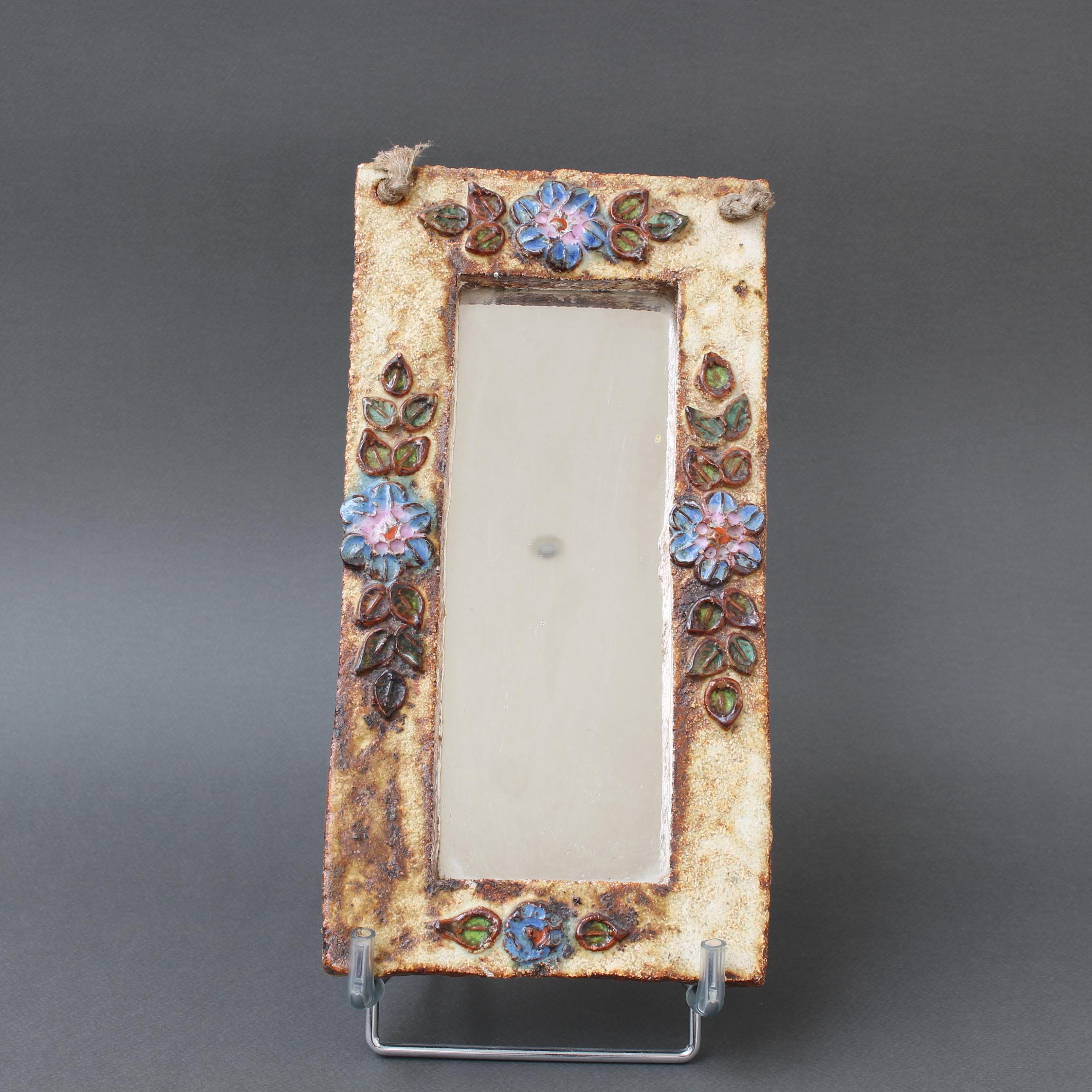 Ceramic flower-motif wall mirror with glazed leaves by La Roue, Vallauris, France (circa 1960s). A charming, decorative piece with rustic but colourful details surrounding the narrow, rectangular mirror. The back side has a hanging string