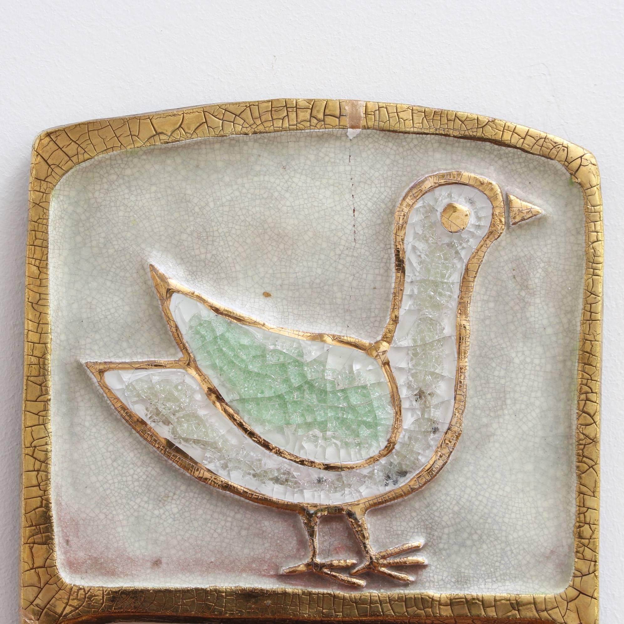 Ceramic wall mirror with gold crackle glaze and stylised bird (circa 1960s) by François Lembo (1930 - 2013). A delightful decorative wall mirror topped with a framed stylised bird which is outlined in gold crackle and filled with colourful cut