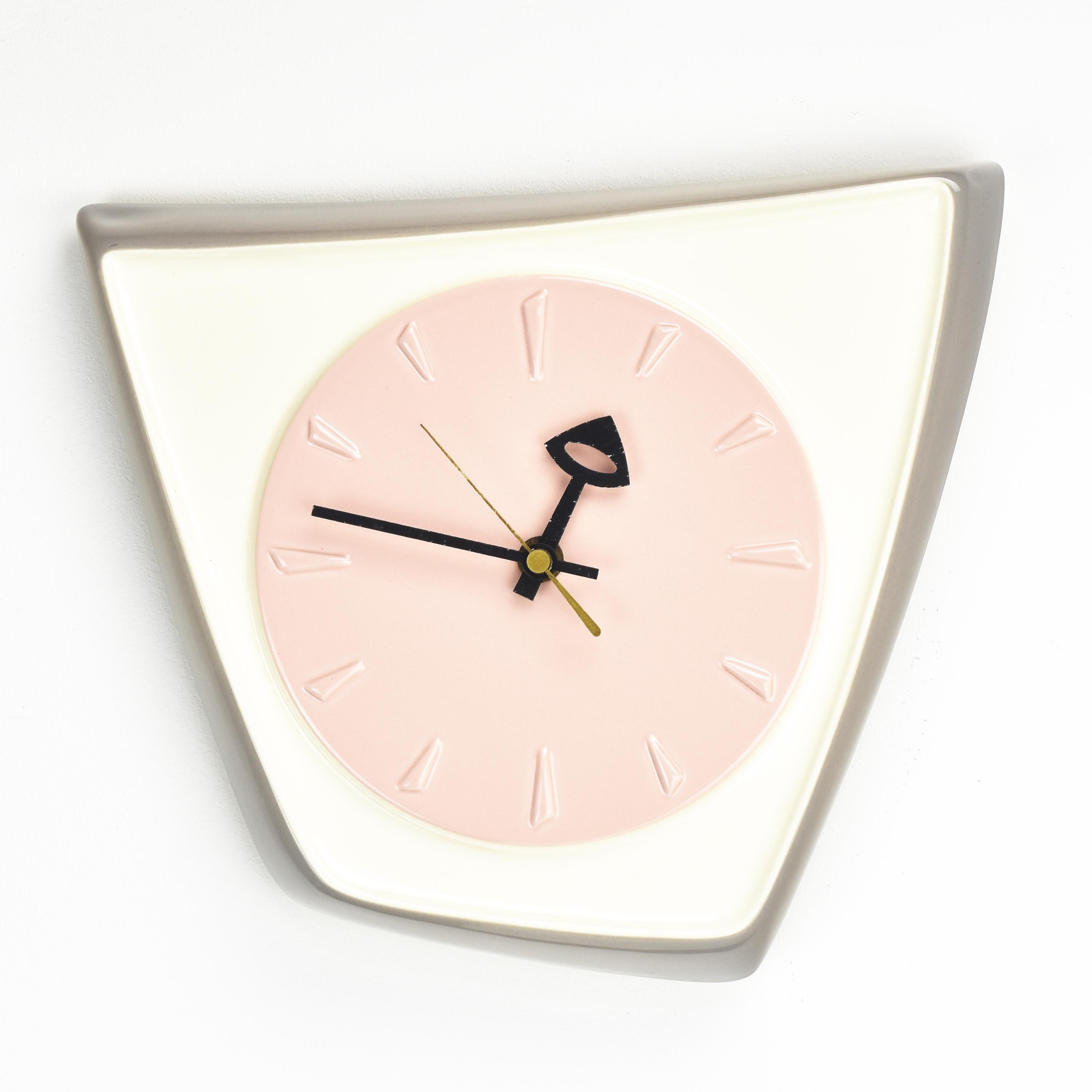 An asymmetrical shaped wall clock with a ceramic shield, glazed in white, light gray, and pastel pink, with black lacquered hands reminiscent of the designs of George Nelson, probably made by Kienzle in the 1950s. 

This clock would be a unique