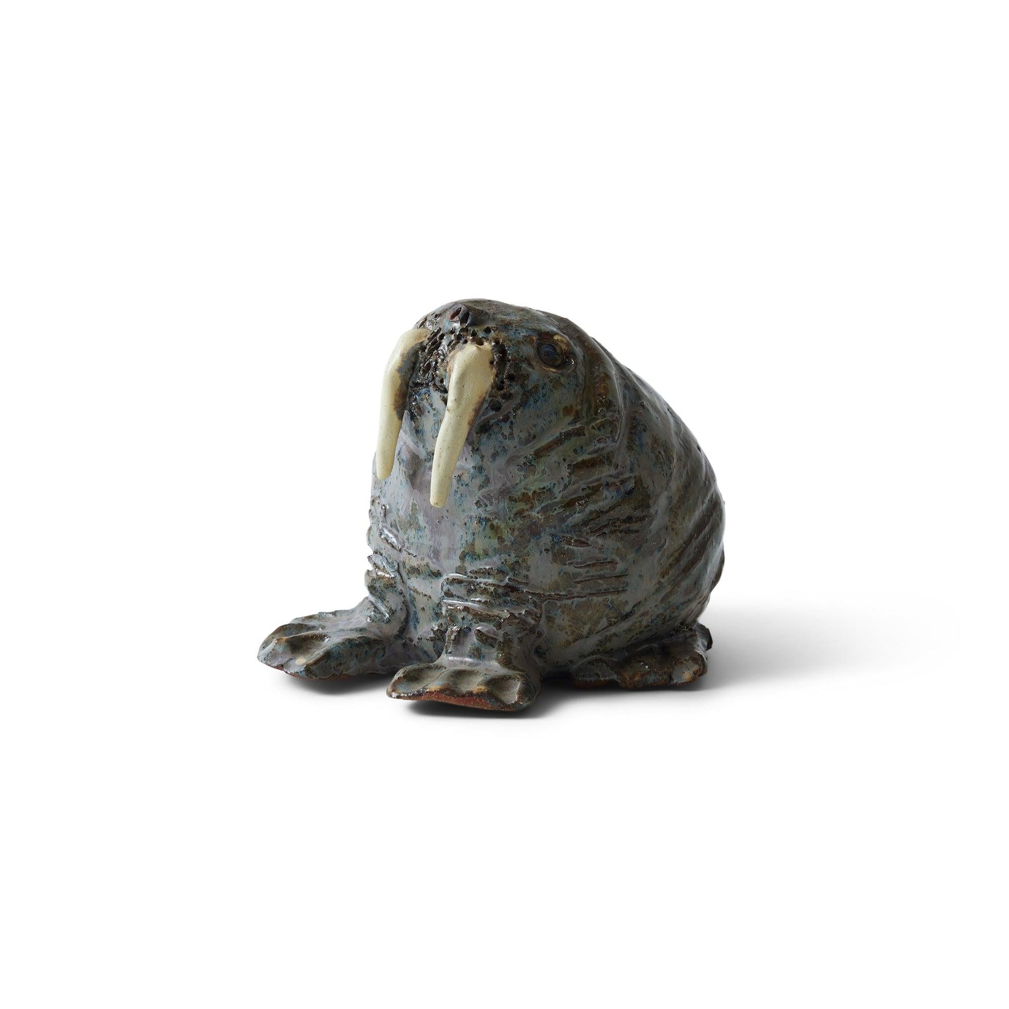 Una piccola statuetta di animale di tricheco in ceramica smaltata, firmata.