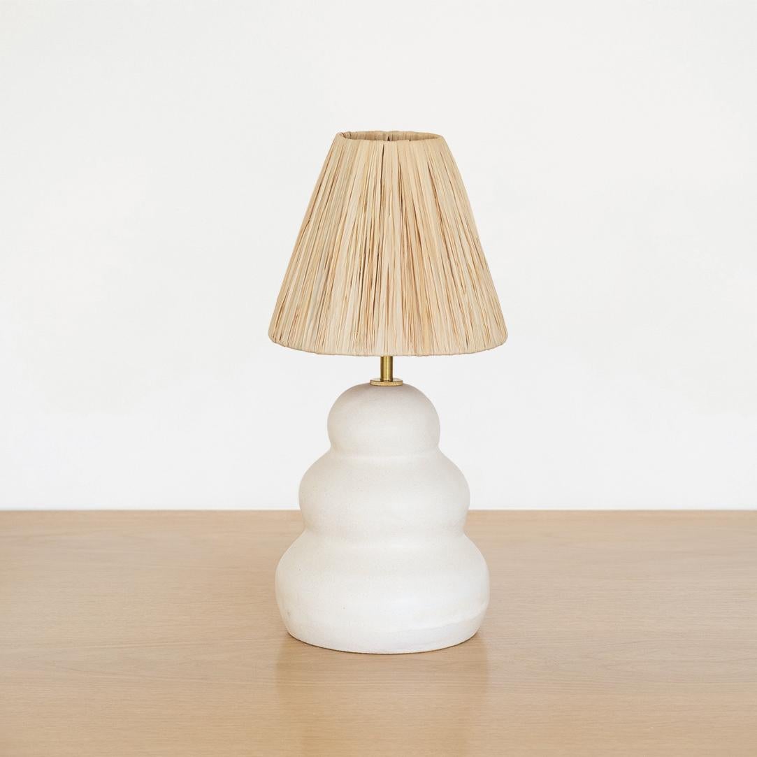 Newly made ceramic lamp in a wavy column form handmade from terracotta and white glaze. New natural raffia shade, brass stem neck, and new white cloth cord wiring with switch. Modern organic form with a nice mix of materials. Hand made in Spain.