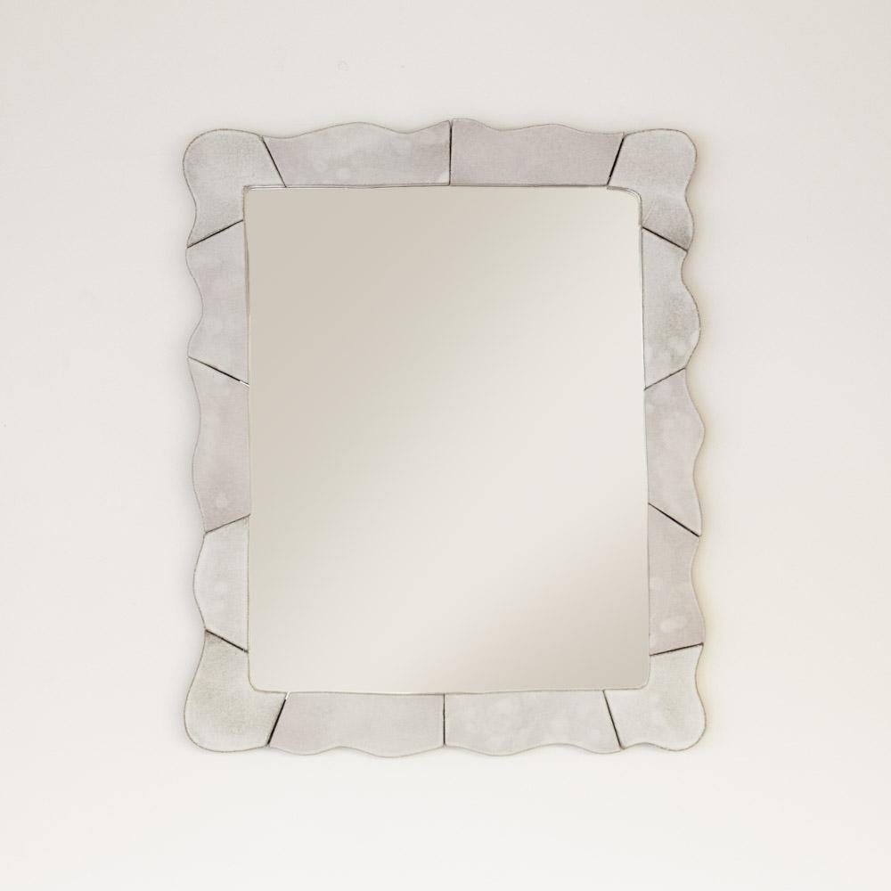 Miroir en céramique ondulée de fabrication récente. Des sections de céramique sculptées à la main sont assemblées pour créer un magnifique cadre rectangulaire ondulé. La glaçure blanche sur la terre cuite crée une belle coloration blanc-gris.