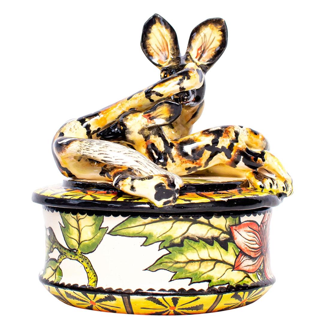 Crafted with precision by Senzo Duma Ceramics in South Africa, this ceramic Wild Dog jewelry box stands 5 inches tall, 4 inches in length, and 4 inches wide. Samkelo's hand-painted motifs reflect the vibrant spirit of African wildlife, portraying