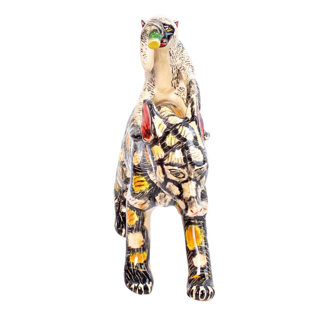 El Perro Salvaje de Cerámica Jinete de Mono, una cautivadora creación de Zimele Ceramics, Sudáfrica, es una pieza destacada de la colección Circo Africano. Esculpida a mano por Sneh y pintada a mano por Selle, esta pieza mide 8 cm de alto, y sus