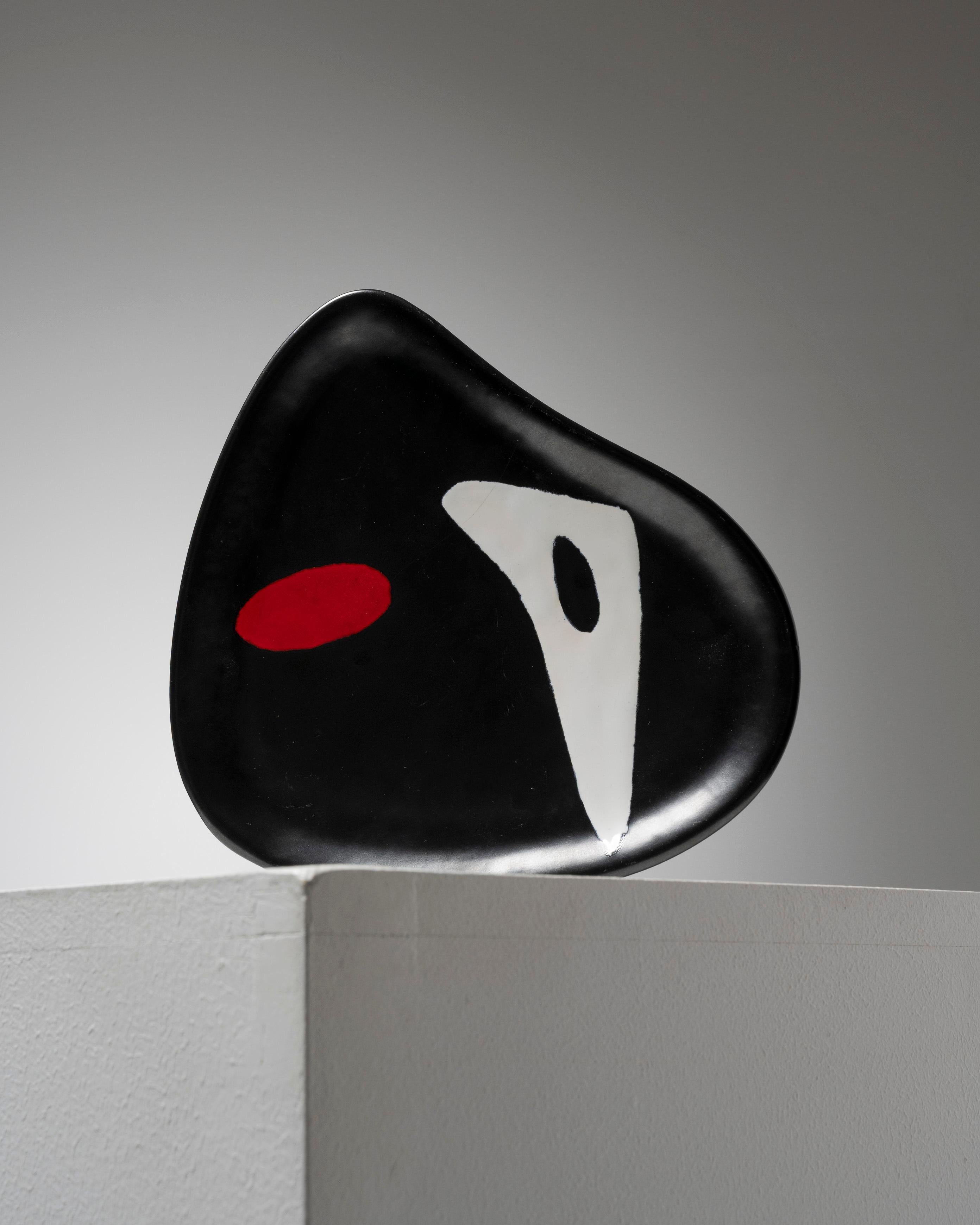 Piatto o cestino a forma libera in ceramica di Denise and Denise Orlando, realizzato negli anni Cinquanta. Su uno sfondo nero smaltato con un disegno astratto rosso e bianco, questo pezzo è un esempio lampante del loro approccio avanguardistico alla