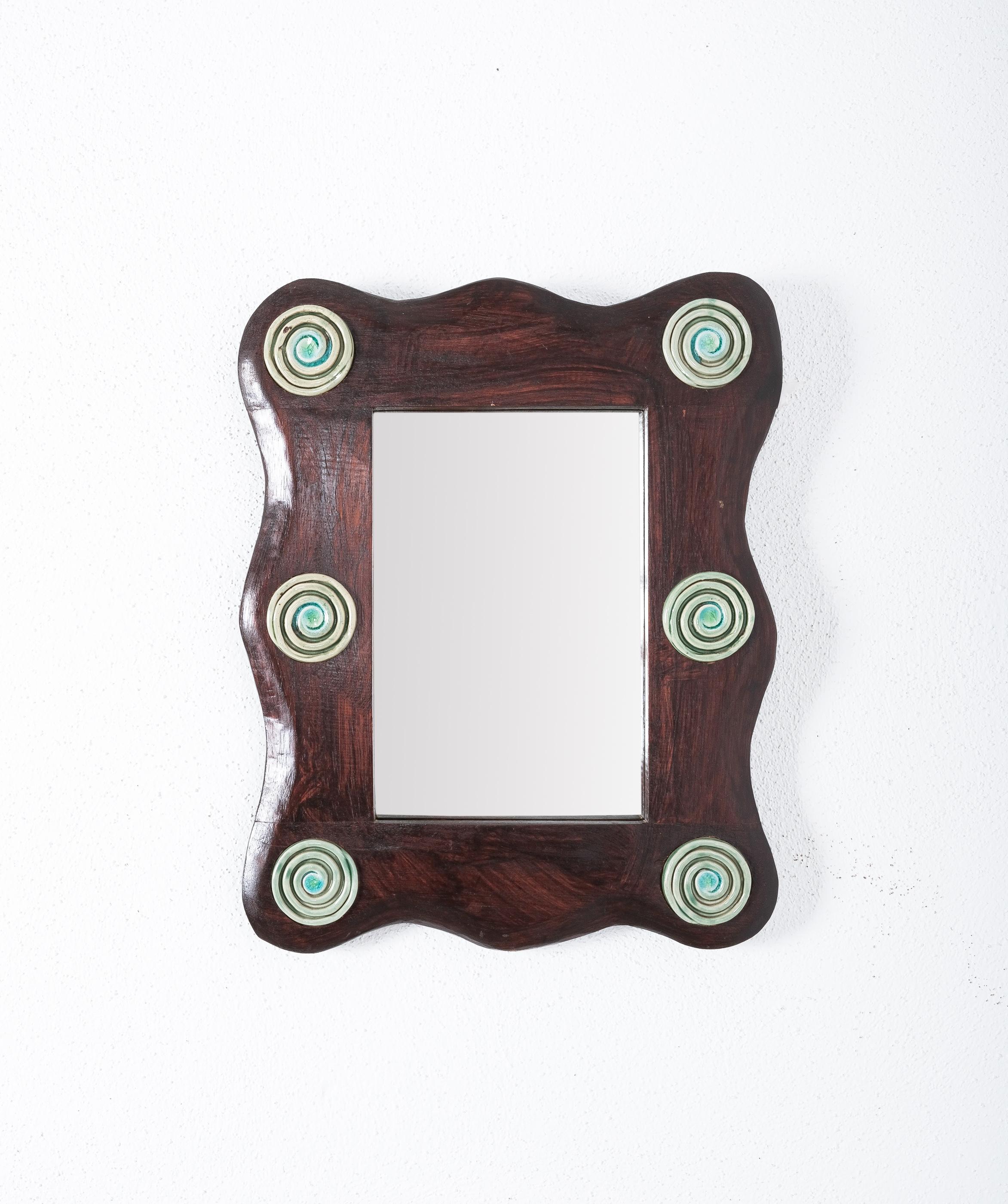 Wooden mirror with ceramic details , France circa 1950.

Mid-century french brutalist wooden frame mirror with ceramic spiral inlayed in the frame. Very decorative. It’s in great condition, the mirror glass shows no staining.
Dimensions are: