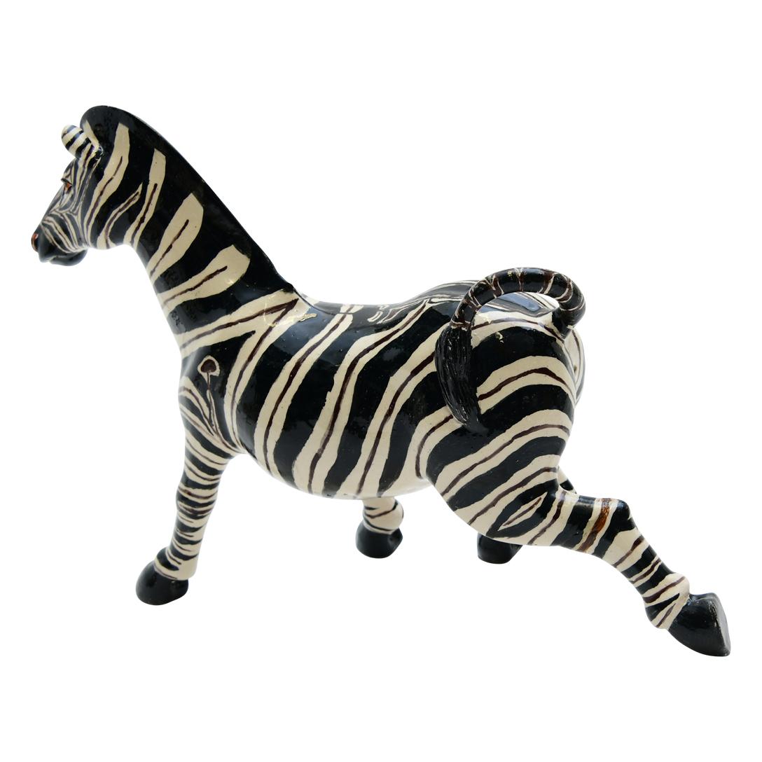 Imvelo Natural Art presents a captivating ceramic Zebra sculpture from South Africa. Hand-sculpted by Bernard and hand-painted by Gabriel, this piece stands 9 inches high, 12 inches long, and 5 inches wide. The sculpture portrays a zebra in a