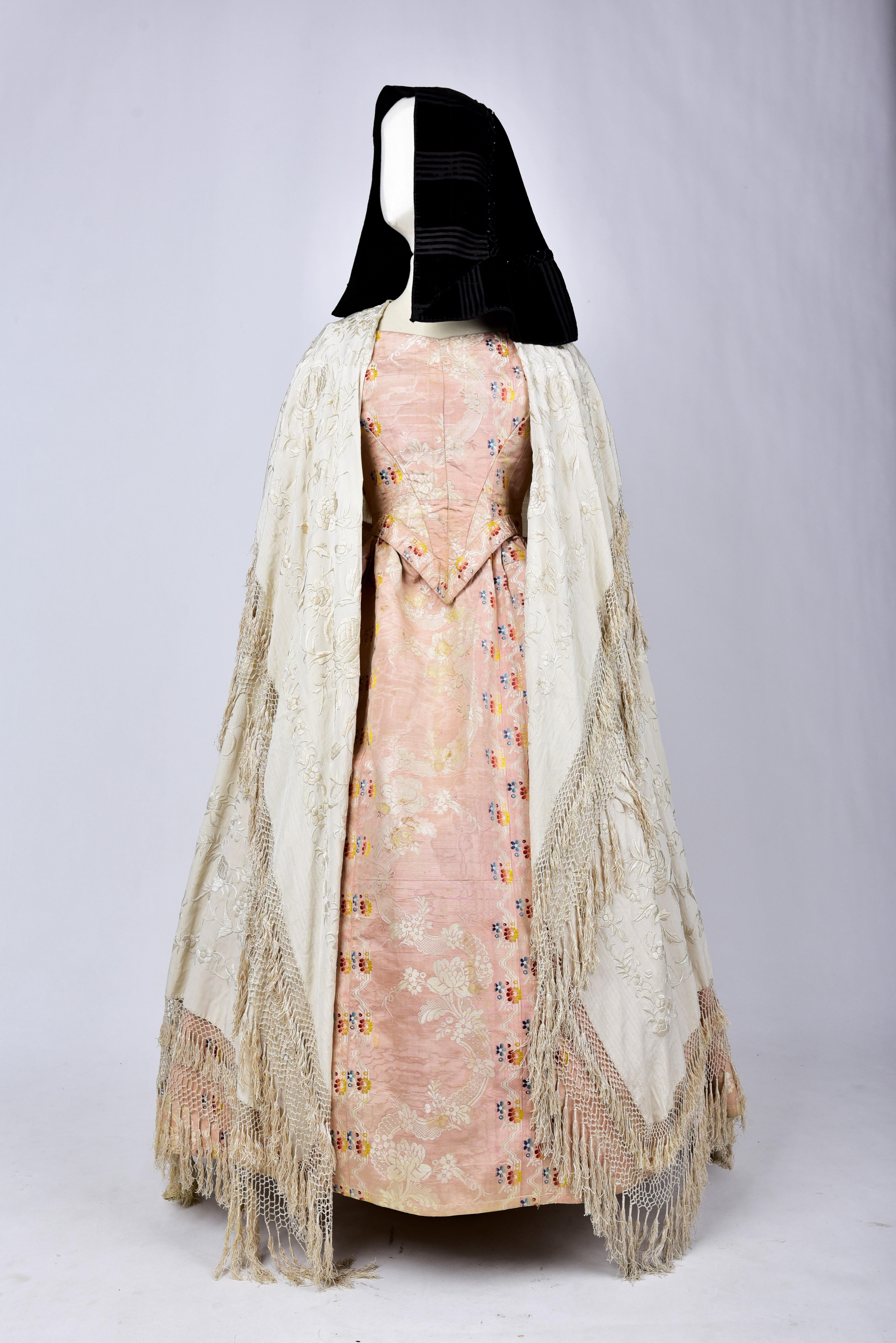 Circa 1860
Spain

Spanish festive costume composed of a brocaded silk moire crinoline dress, a black velvet mantilla embroidered with jet pearls and a cream silk crepe embroidered shawl called Manila. The set was collected in Madrid and is worthy of