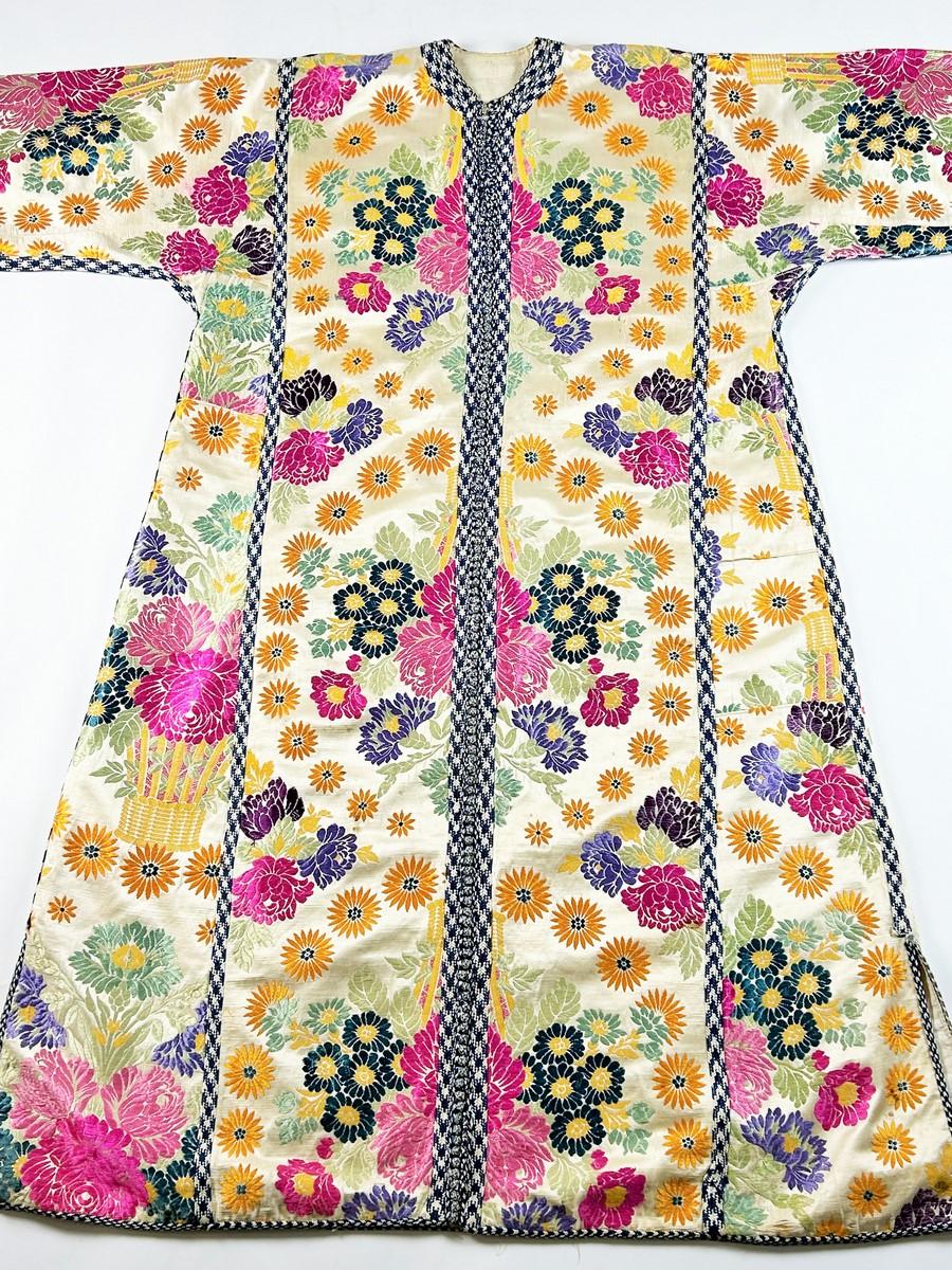 Circa 1900-1930
Morocco
A Moroccan ceremonial kaftan in brocaded silk lampas dating from the first third of the 20th century. Cream satin brocaded background with large floral baskets adorned with daisy medallions, produced in Lyon for the Moroccan