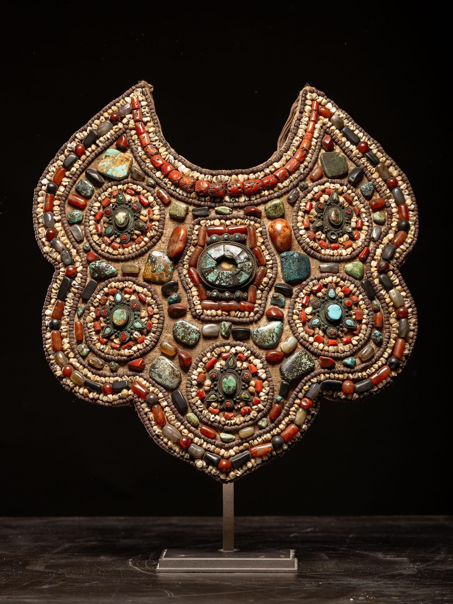 Old large pectoral necklace in the shape of a breastplate, originating from Tibet. Magnificent color work with a mixture of turquoise stones, red beads, silver and copper. The support is composed of a fabric mattress. Several reliquaries set with