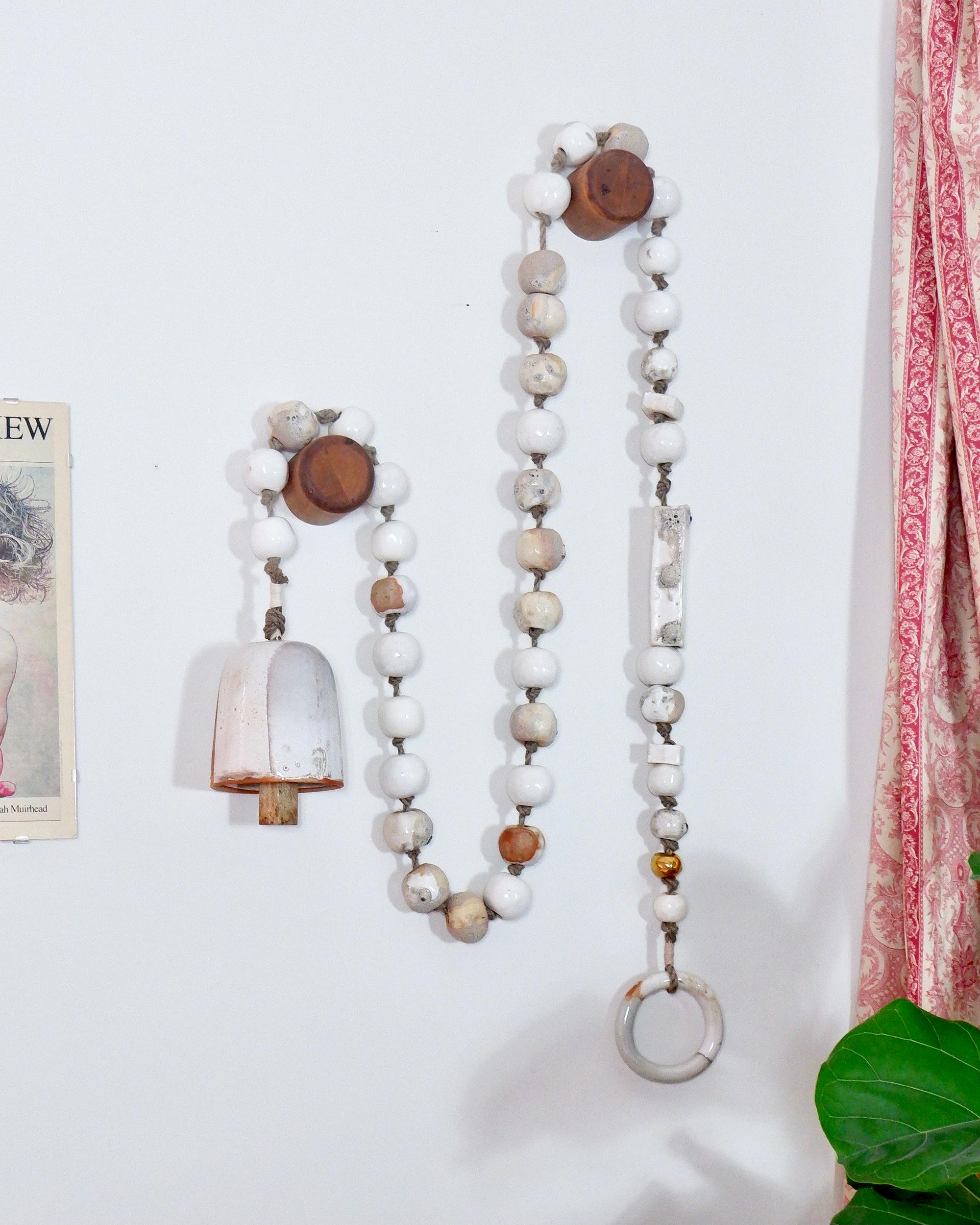 These striking hand-made beads add a bit of primitive character to your decor or personal style. The Lichen bead hanging features one-of-a-kind wood-fired beads and a bell. Drape on a wall as a garland or use as a wall hanging. Each strand comes
