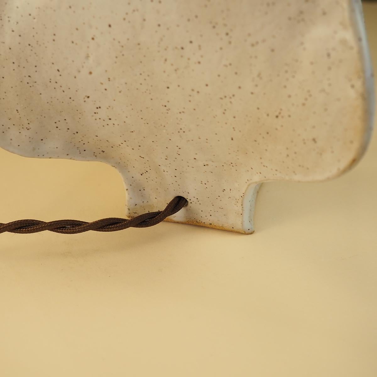 Inspirada en las formas orgánicas y ondulantes de los cactus del desierto, esta lámpara logra un equilibrio entre minimalismo y alegría.  

Cada lámpara se construye a mano con un cuerpo de arcilla moteada utilizando un método de construcción de