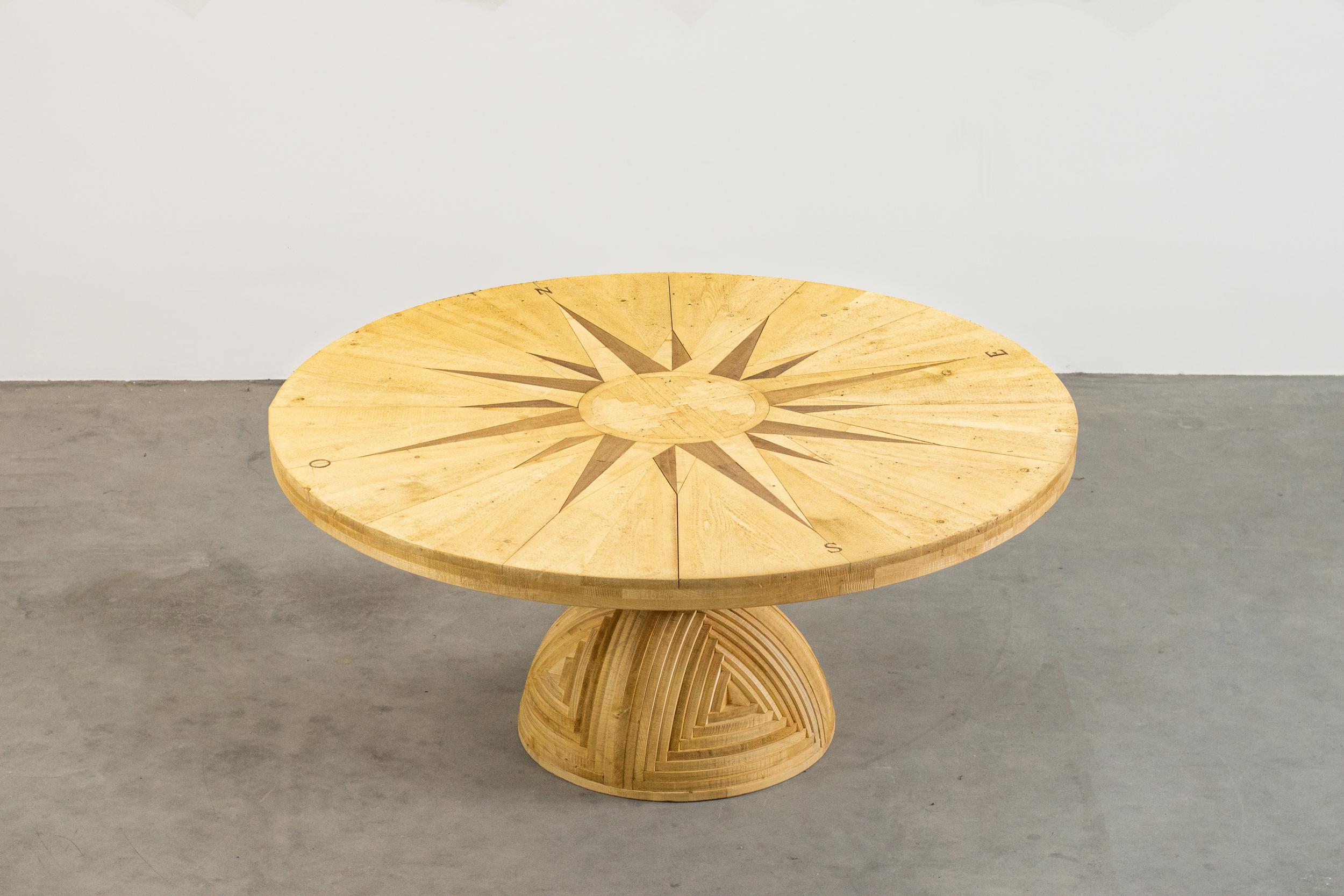 A large dining table model La Rosa dei Venti, part of the Mobili nella Valle series, it's entirely realized in pinewood, with inlays on table-top, it was designed by Mario Ceroli and produced by Poltronova in the 1970s.

The beautiful inlays on