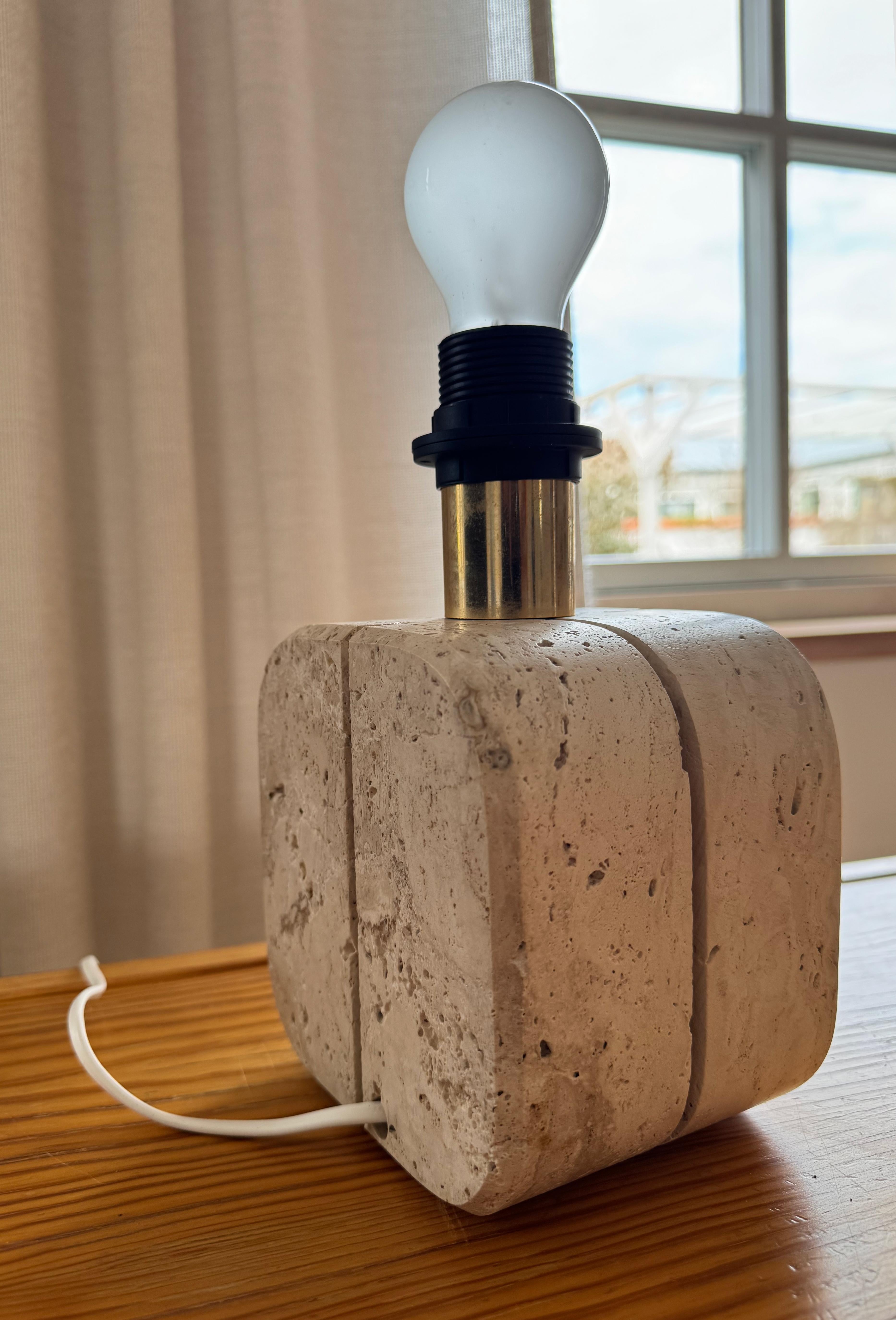 The Cerri Nestore Table Lamp in Travertine, crafted in the 1970s in Italy, exudes bold elegance. Each piece features meticulous groove detailing cut into the travertine. The design blend classic craftsmanship with modern functionality. The lamp