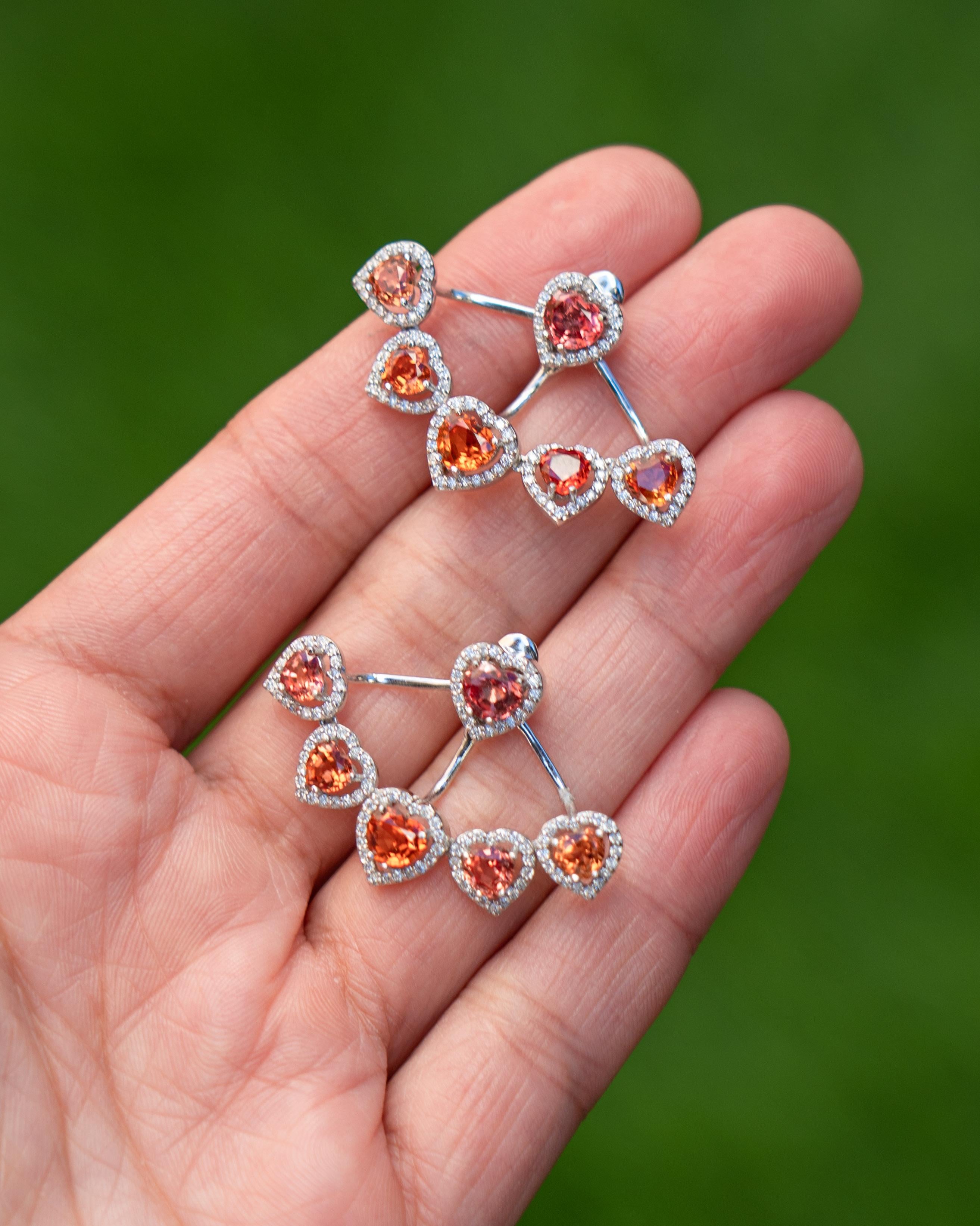 These gorgeous earrings set in orange colored Sapphires can be worn as a single stud and also a more elegant earrings with a 5 piece heart shape orange sapphire extension. The total weight of the sapphires is 5.90 Carats and there are 224 pieces of
