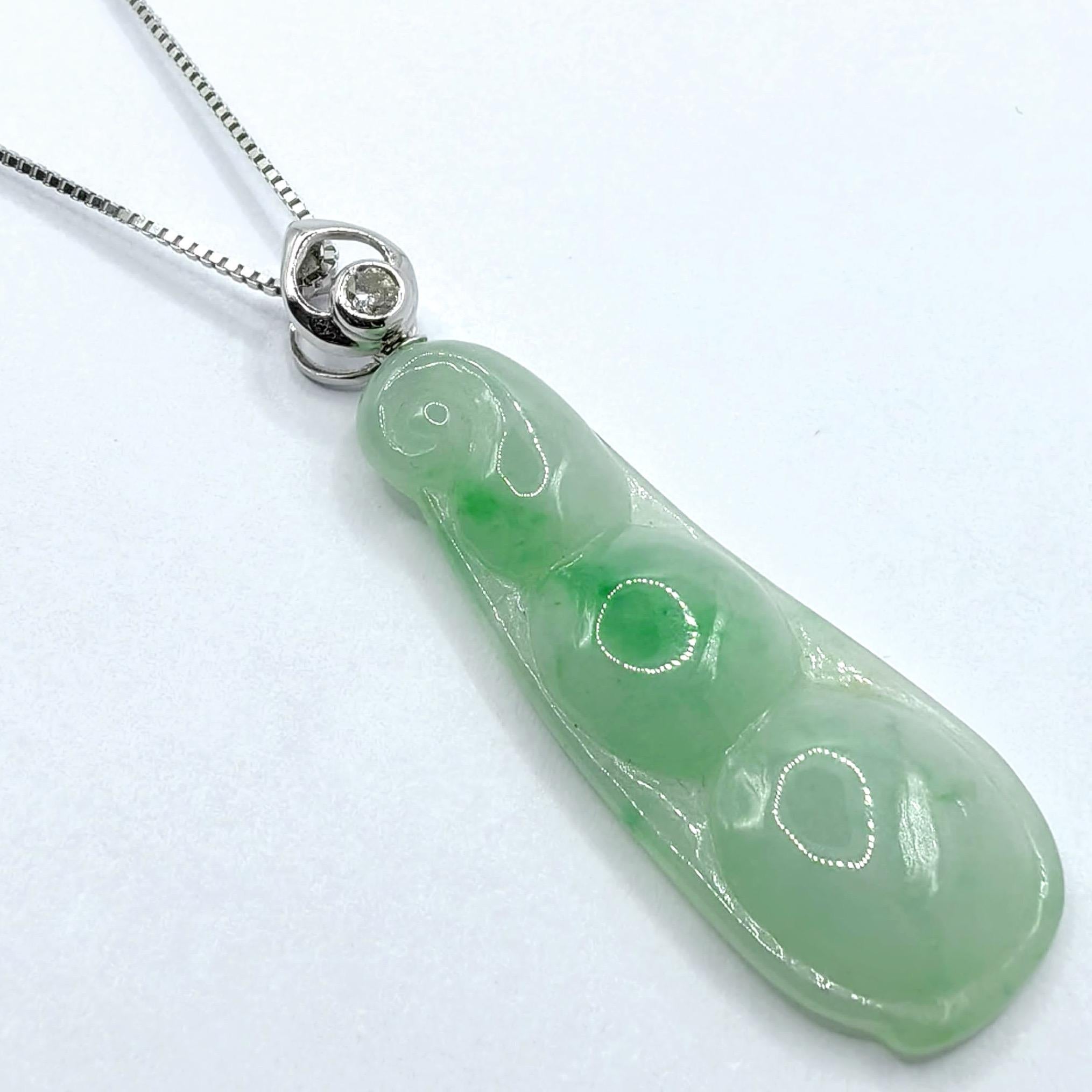 This exquisite pendant showcases the serene beauty of translucent light-green jadeite with vivid apple-green color concentrations, masterfully carved into the traditional bean pod design that symbolizes abundance and prosperity in Chinese culture.