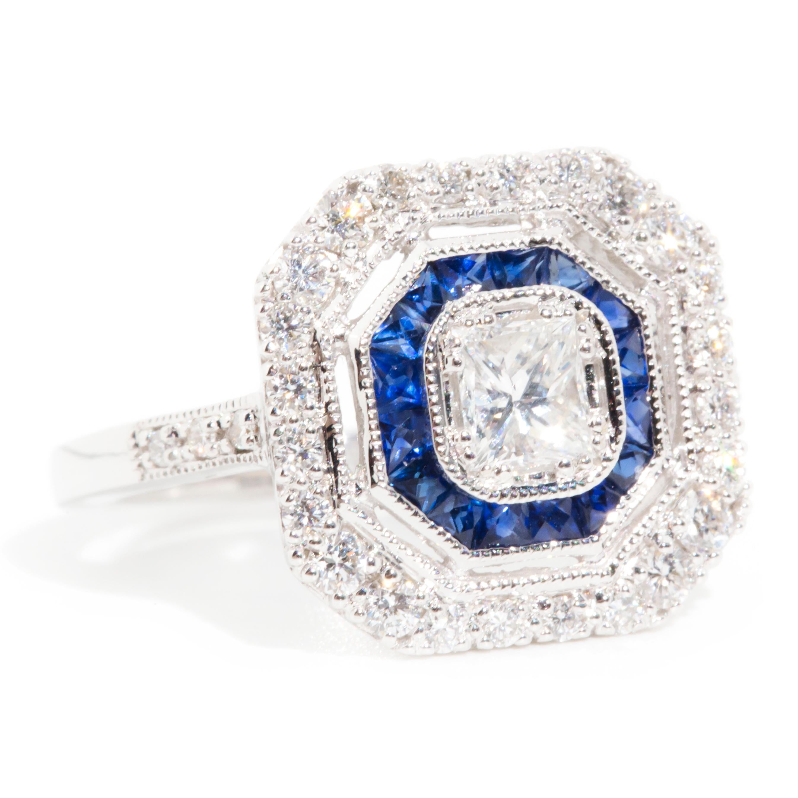 Forged in 18 carat white gold, this stunning art deco-inspired halo ring features a central striking princess cut diamond encompassed by gorgeous custom cut bright blue sapphires and a glittering halo of sparkling round brilliant cut diamonds. We