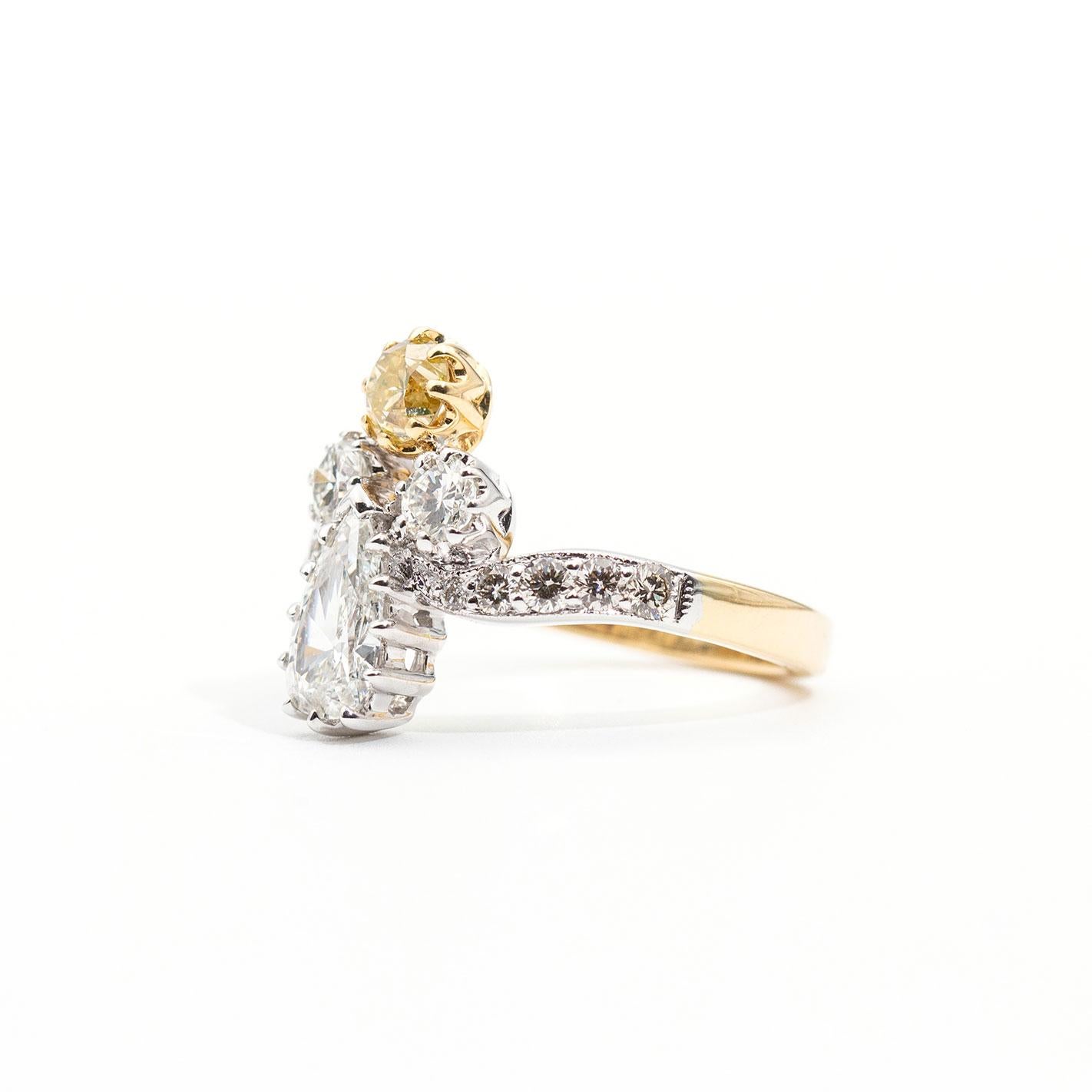 This alluring vintage inspired ring is forged in 18 carat white and yellow gold and features a stunning certified 0.70 carat pear shape diamond with an eye-catching certified natural light fancy yellow round brilliant cut diamond complimented by two