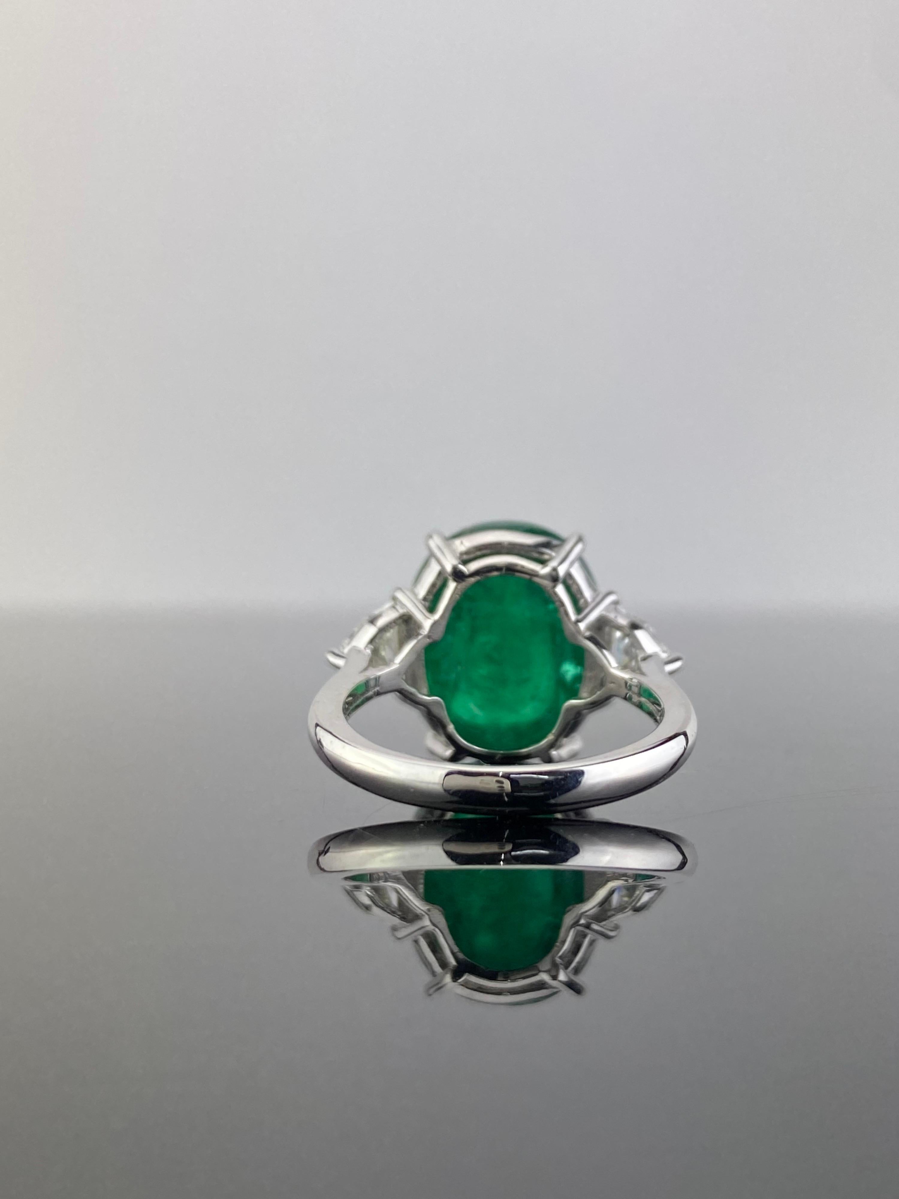 A 10.55 carat sugarloaf shaped Zambian Emerald and 0.59 carat cadillac shaped White Diamonds three stone engagement ring, set in solid 18K White Gold. The Emerald is transparent, with an ideal vivid green color and great luster. The ring is