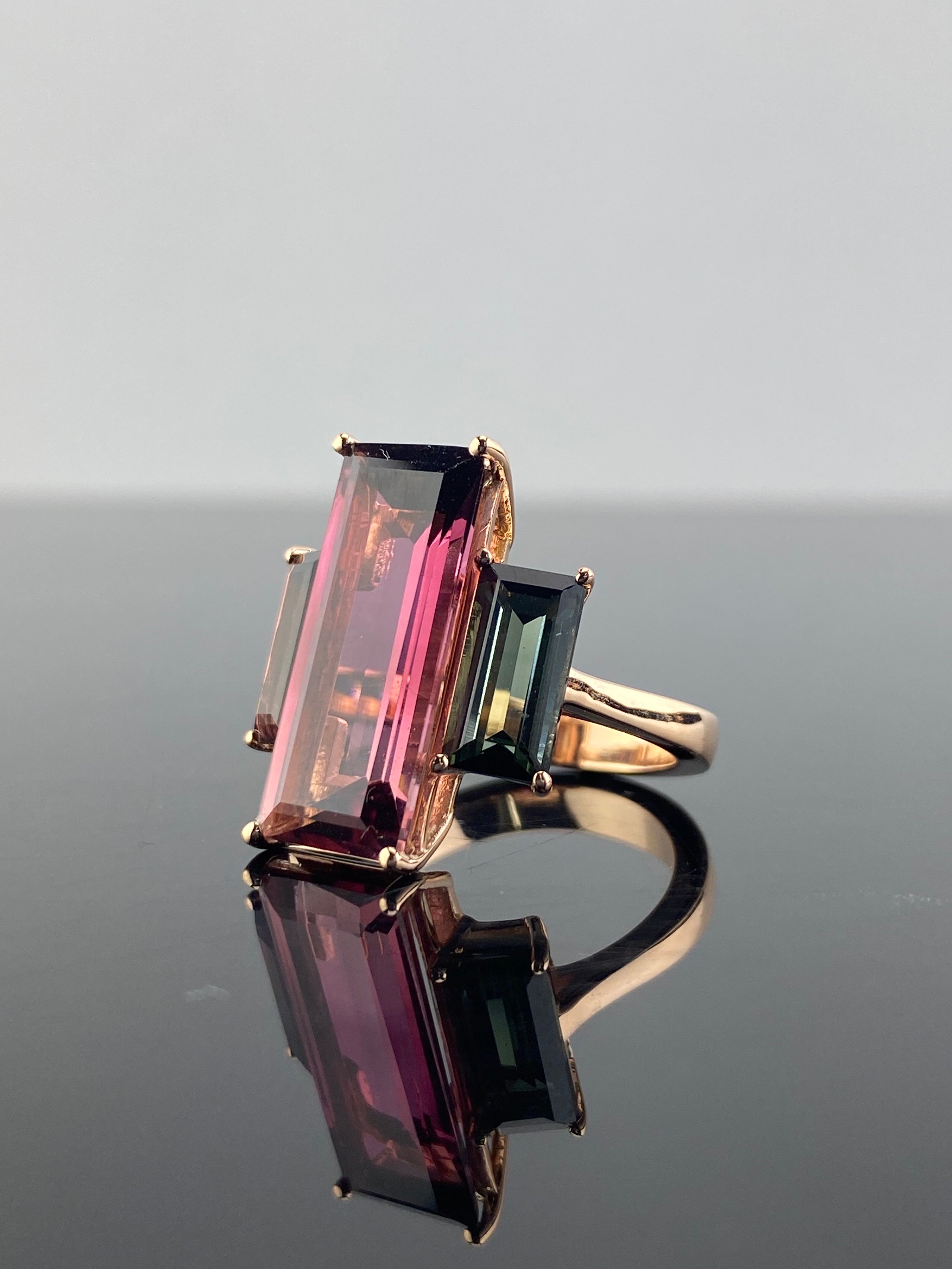 an eye-catching 7.83 carat Pink Tourmaline center stone, with 3.03 carat Green and Brown Tourmaline side stones. The Emerald cut Tourmalines are absolutely natural with no inclusions and great color, and are set in solid 18K Rose Gold. The ring is