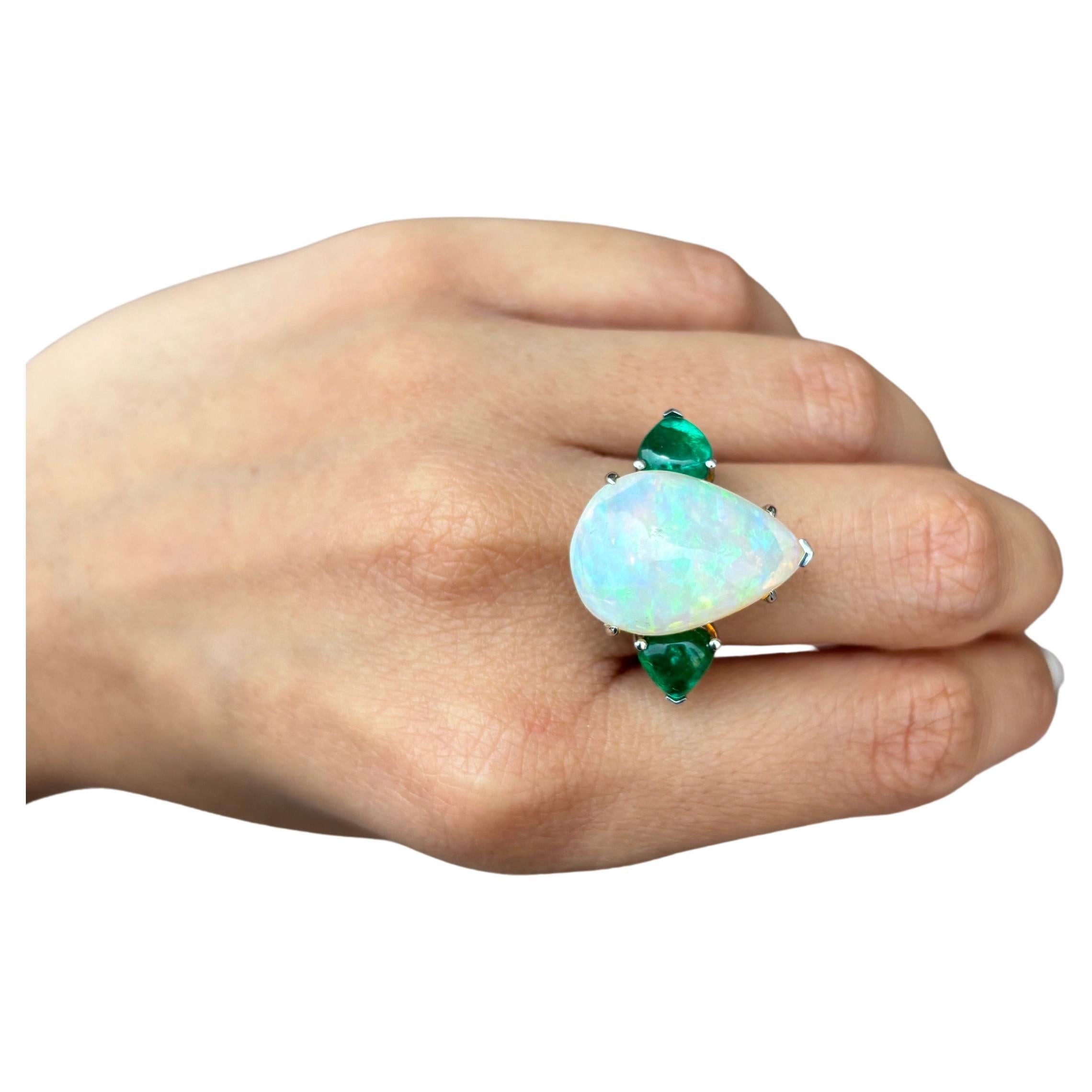 Make a statement with this beautiful pear shape cabochon 11.36 carat Ethiopian Opal and pear shape cabochon 2.51 carat Zambian Emerald side stone ring. The center stone has an ideal cut, and play of color, making it a great ring to own! The Emerald