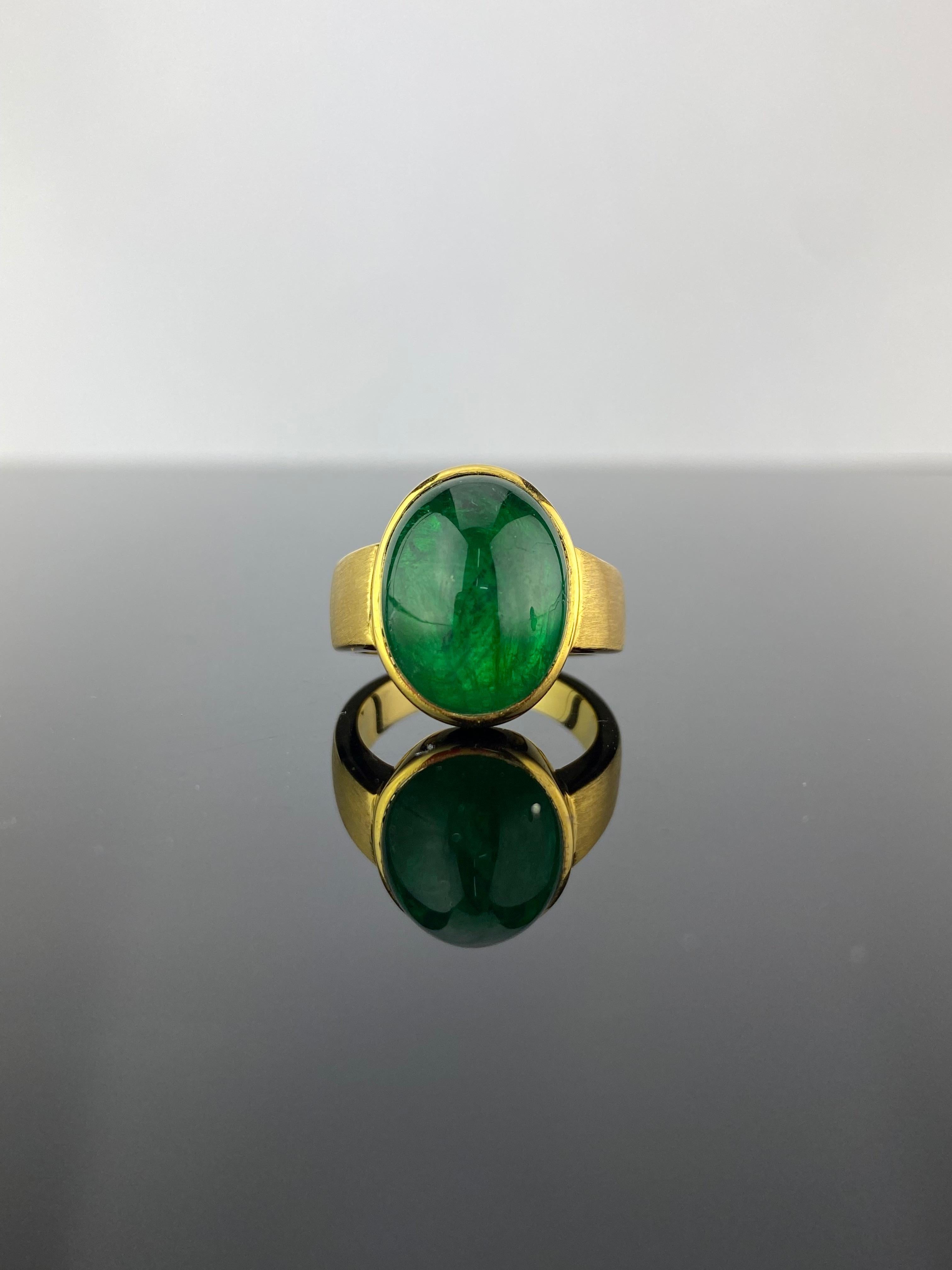 A stunning 12.05 carat Zambian Emerald cabochon and matte finish 18K Yellow Gold ring. The natural Emerald centre stone is transparent with an ideal vivid green color, and the matte finish gold gives the ring an antique look. The ring is currently