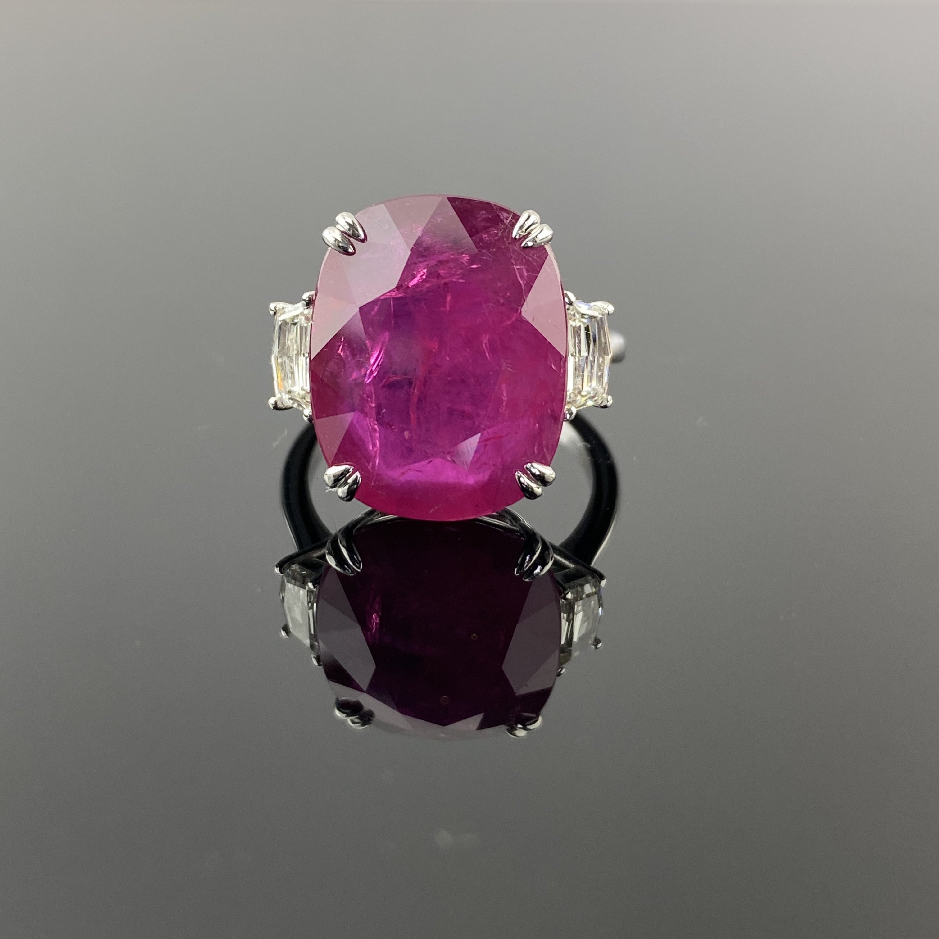 A beautiful ring set in 18K White Gold featuring a 12.51 Carat natural, red, heated Burma Ruby and 2 cadillac shaped diamonds weighing 0.60 Carats total.  

Rubies are referred to as 