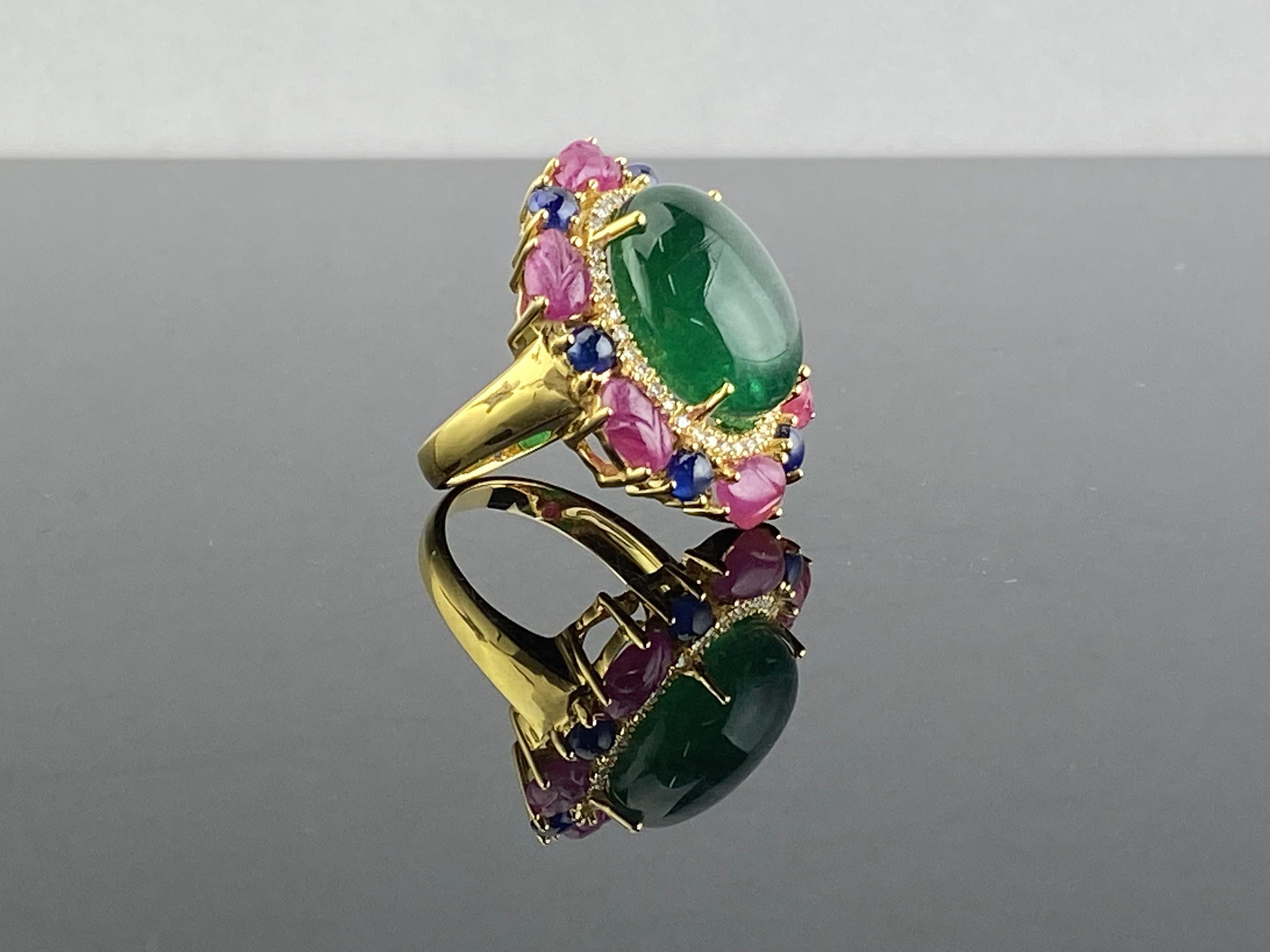 One of a kind art-deco inspired multi-gemstone tutti-frutti cocktail ring. 
A stunning 12.80 Zambian Emerald cabochon center stone (ideal vivid green color, transparent, great luster) surrounded with Diamonds, Burmese Ruby carvings, and Sapphires -