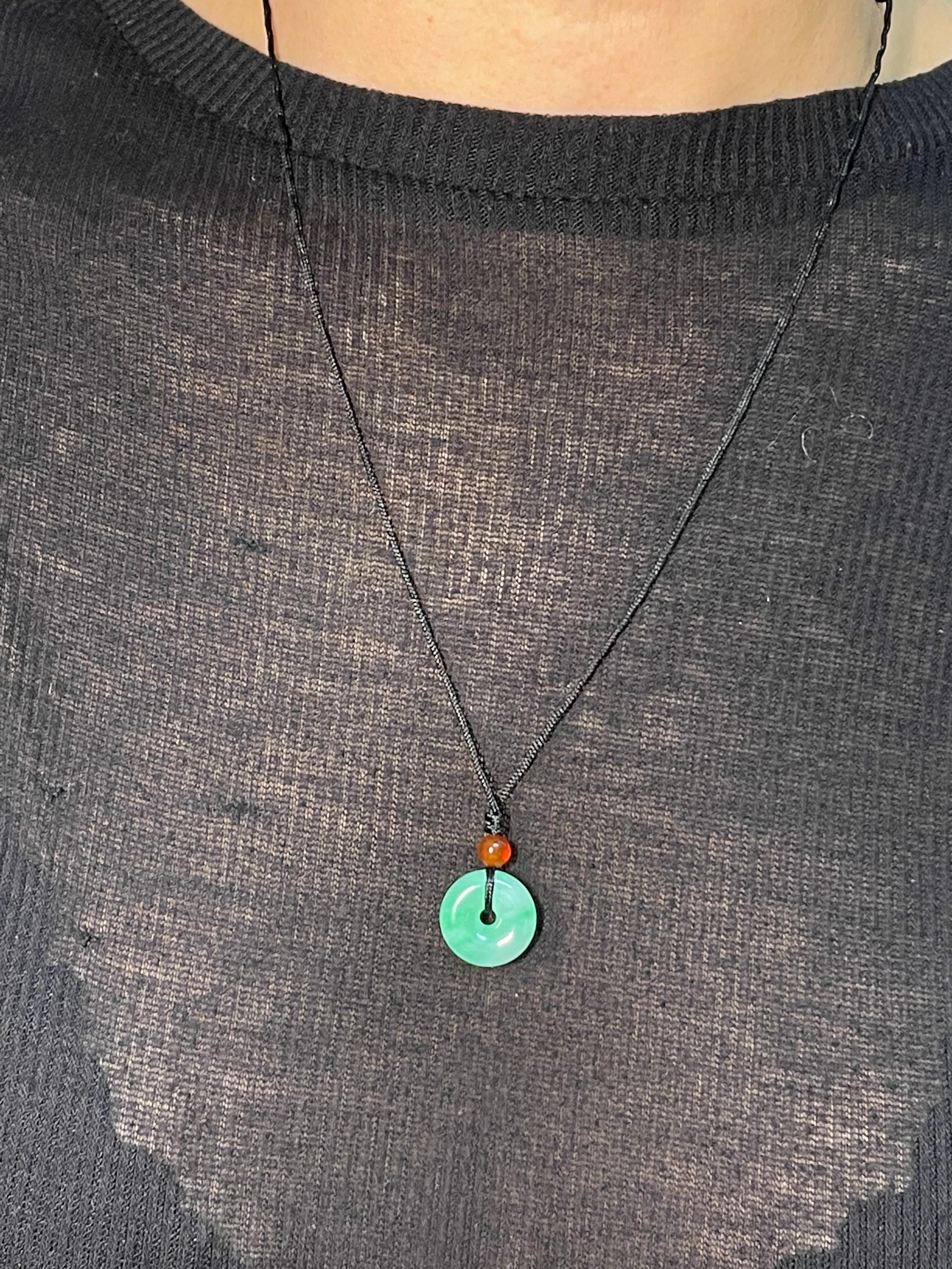 Please check out the HD video. This is certified natural jadeite jade. The jade donut (also know as a PEACE pendant) is paired with a nice red agate bead. The apple green jade and red agate are held together with a traditional Chinese string cord
