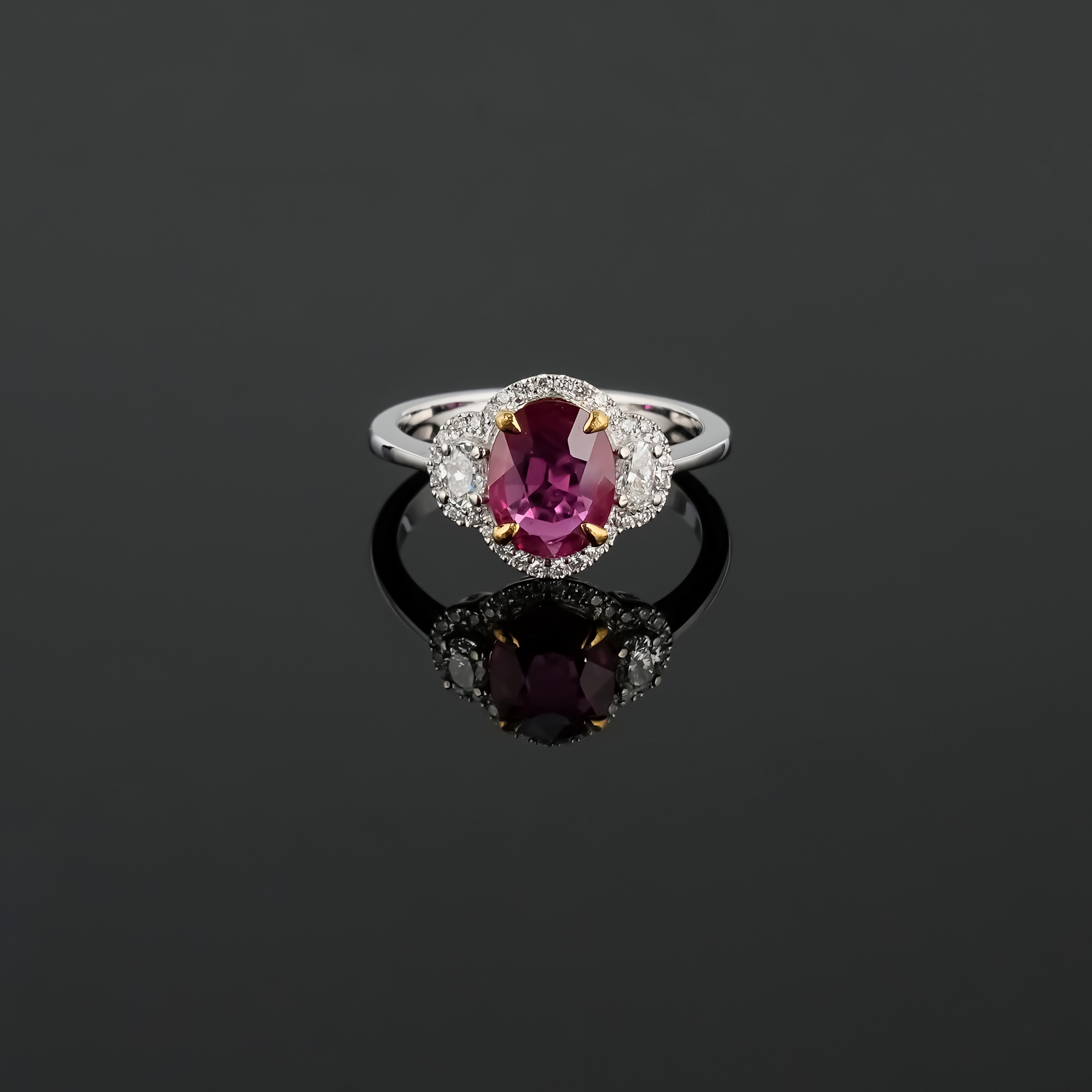 A beautiful, certified 1.60 carat oval shaped Mozambique Ruby center stone engagement ring, adorned with 0.28 carat oval shape Diamond side stones, and 0.19 carat round Diamonds. The Ruby is transparent, with a beautiful vivid red color and amazing