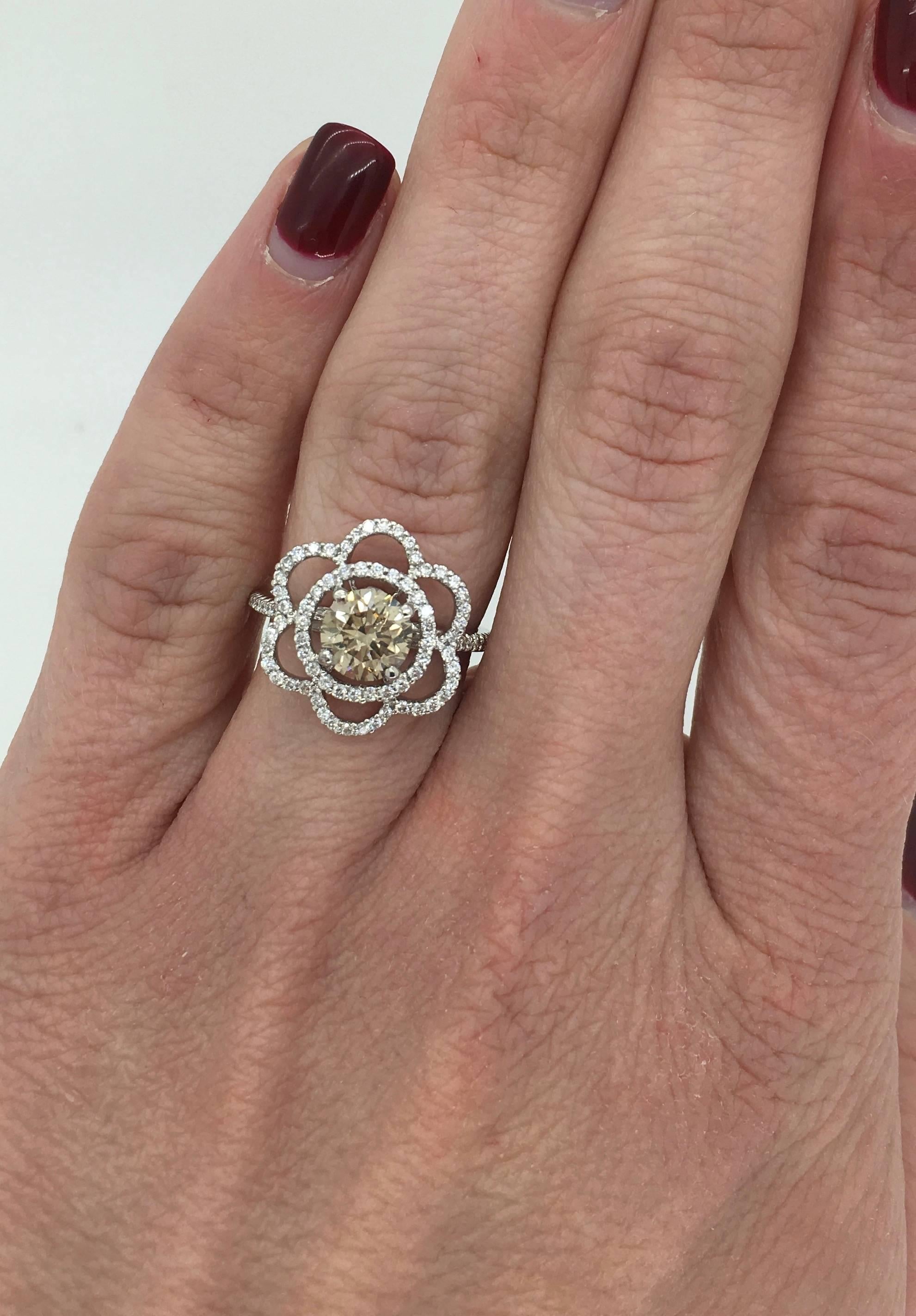 This flower shaped ring features a GIA Certified 1.12CT Round Brilliant Cut Diamond with SI1 clarity and Fancy Light Brown Color. There is approximately .50CTW of additional Round Brilliant Cut Diamonds surrounding the featured diamond; these