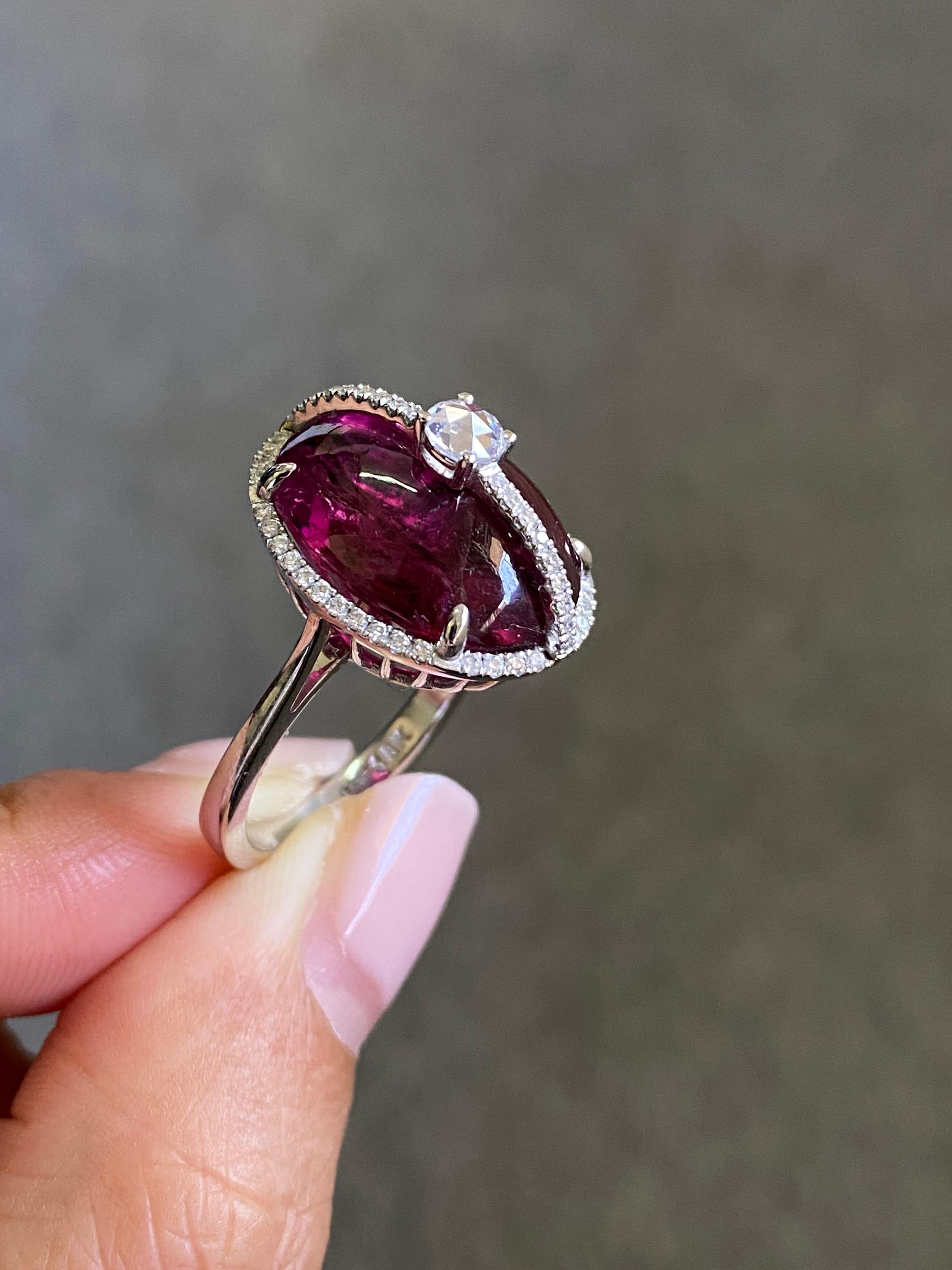 A stunning 16.47 carat natural pink Rubelite Tourmaline cabochon cocktail ring adorned with Diamonds and set in 18K White Gold. The captivating vivid pink color and great luster of the center stone makes the ring an eye catching statement piece,