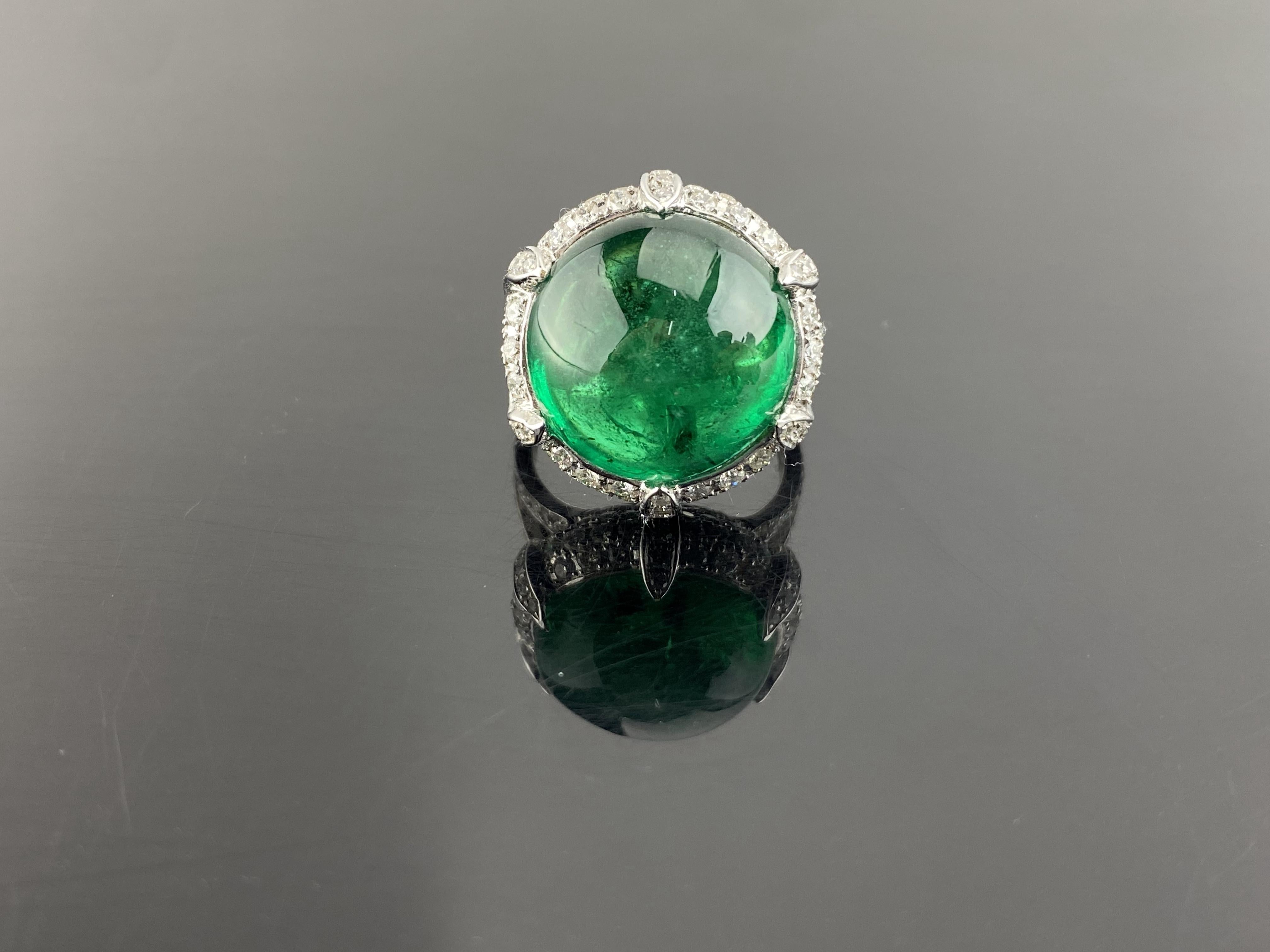 A one of a kind, round shaped cabochon Zambian Emerald weighing 19.30 carats with 2.15 carats of VS quality White Diamonds, all set in 18K solid White Gold. The center stone Emerald is transparent, with a an ideal vivid green color and a beautiful