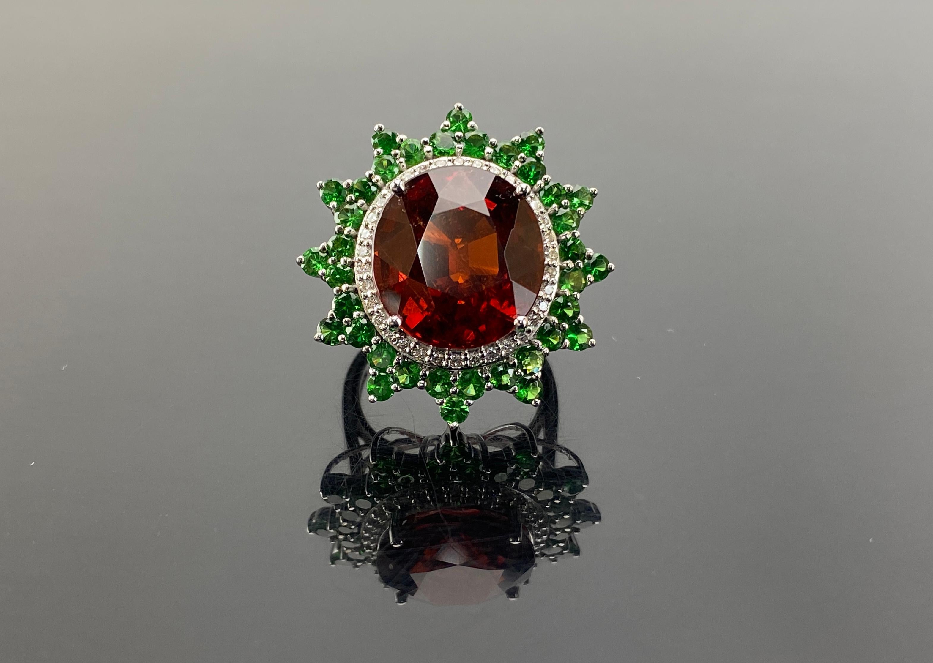 An exceptional 18.53 carat, transparent and fiery orange color Mandarin Garnet center stone accented with uniquely cut round Tsavorites totaling 6.13 ct. The ring is also set with 0.34 carat White Diamonds, G-H color and VVS1 clarity, all set in