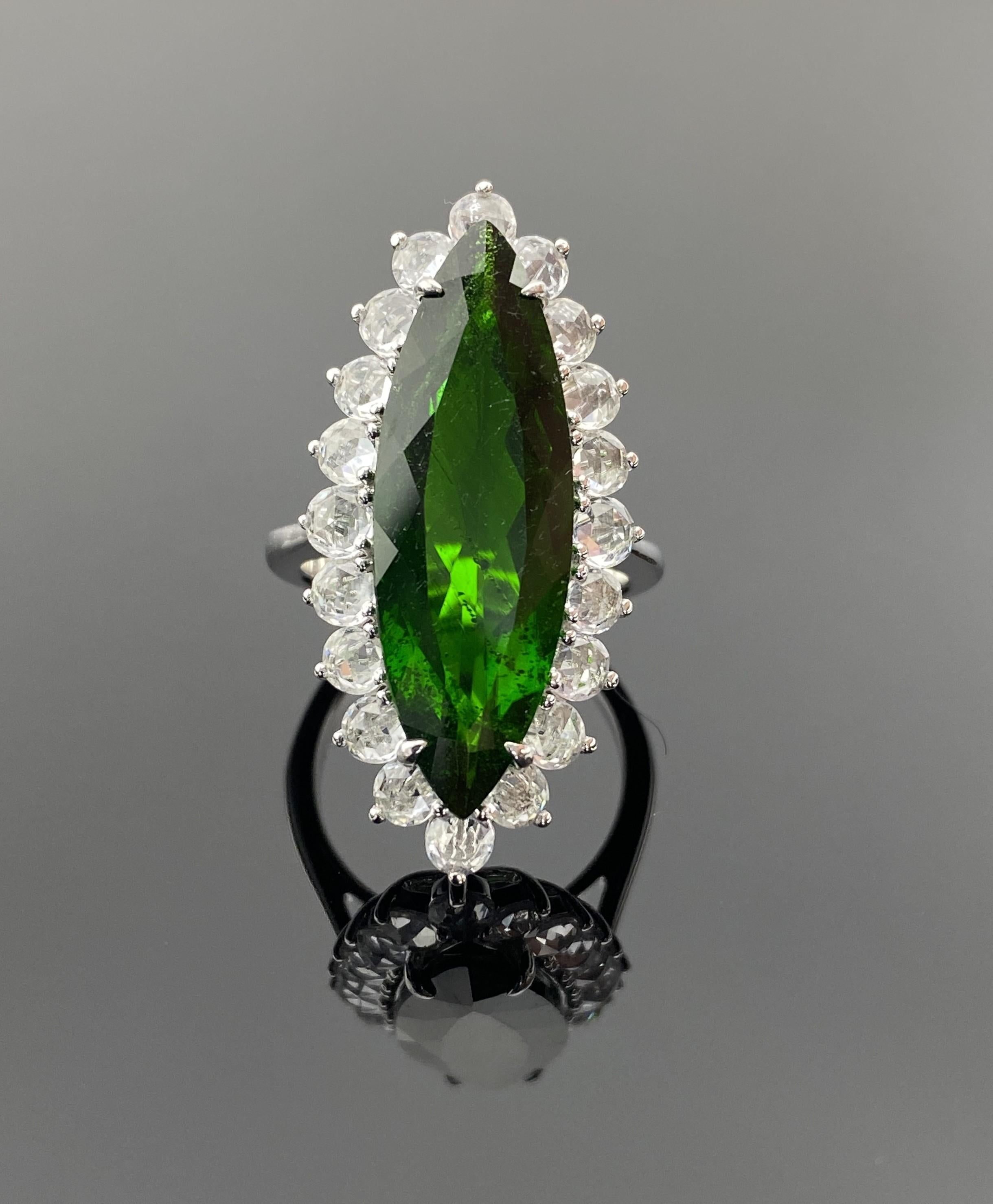 Placez sous les feux de la rampe avec cette époustouflante bague de cocktail en or blanc 18 carats, une véritable pièce d'apparat qui respire le luxe et la sophistication. 

La pièce maîtresse est une extraordinaire tourmaline verte taillée en