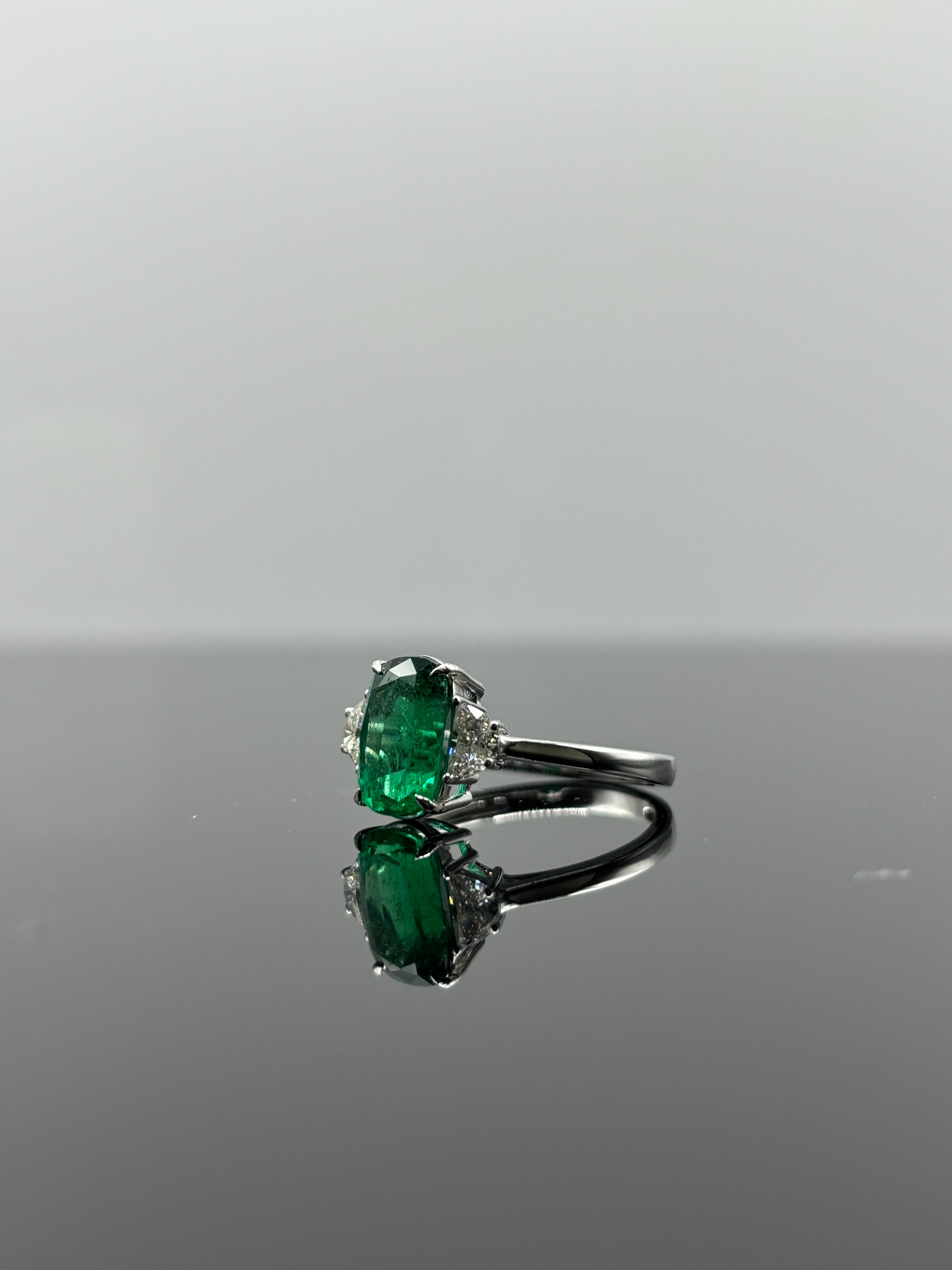 Stunning 2.56 Carat cushion shaped Zambian Emerald and 0.38 carat VS F/G color Diamond, three stone engagement ring. The center stone Emerald is of a very high quality, with vivid green color and transparent. Currently sized at US 7, can be resized.