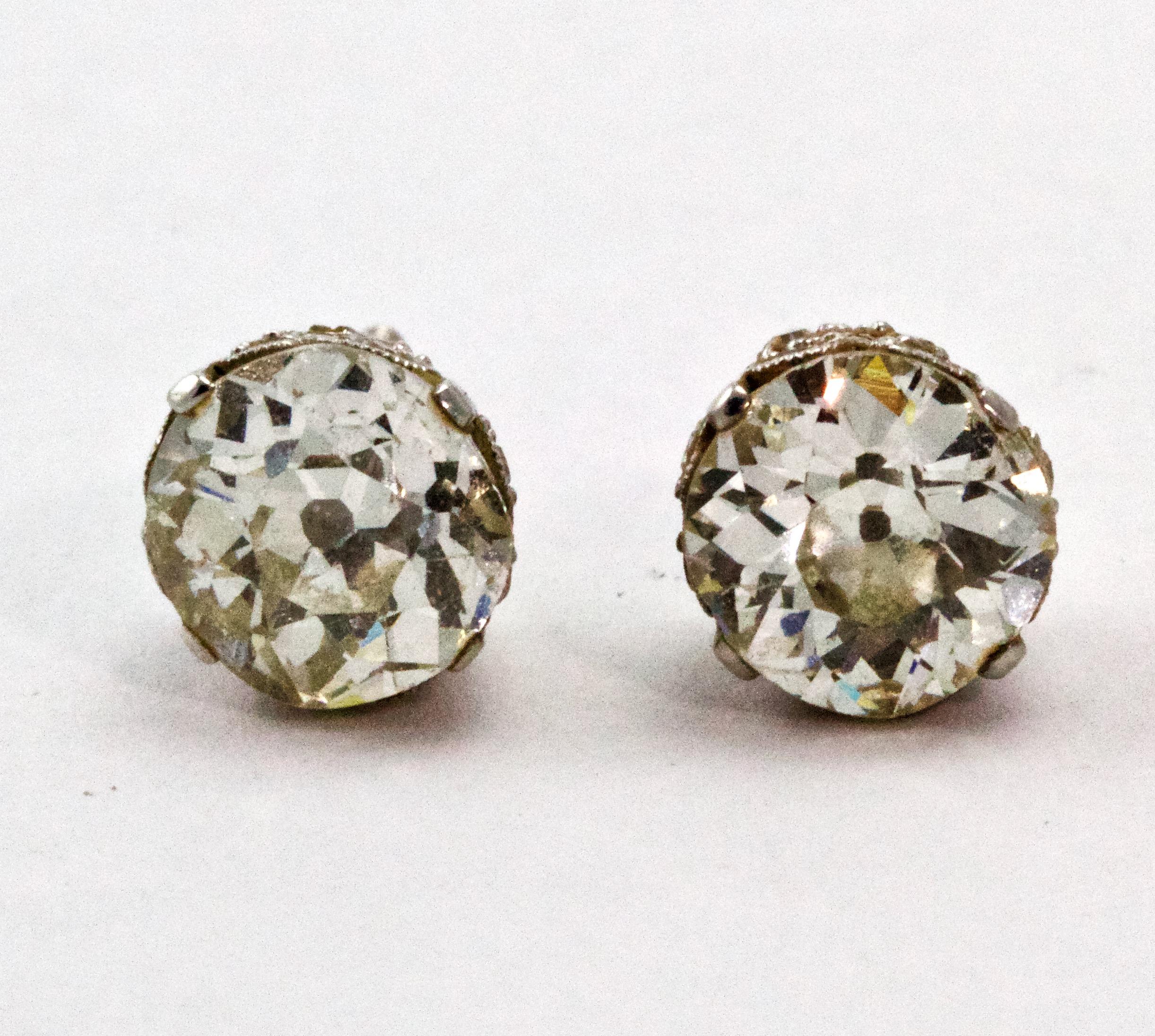 A spectacular pair of Art Deco diamond stud earrings. Showcasing two Old European Cut diamonds in diamond embellished coronet settings, complete with screw back fittings and modelled in platinum throughout. 

Diamonds : Total diamond weight