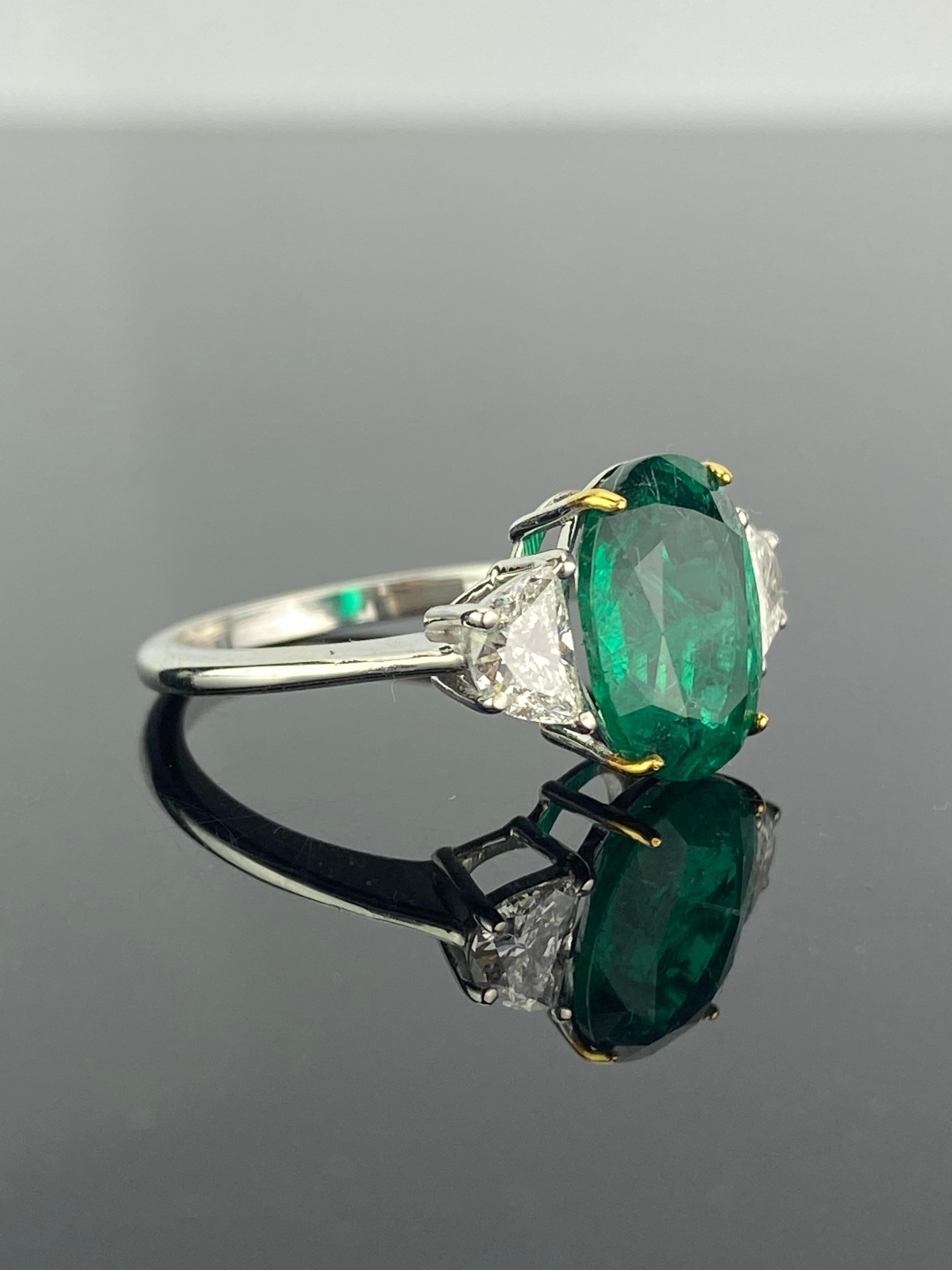 A beautiful three stone engagement ring, with a 2.68 carat transparent natural Zambian Emerald centre stone and 0.53 carat half-moon side stone diamonds. The emerald is of great lustre and has an ideal colour with very few minor inclusions. All set