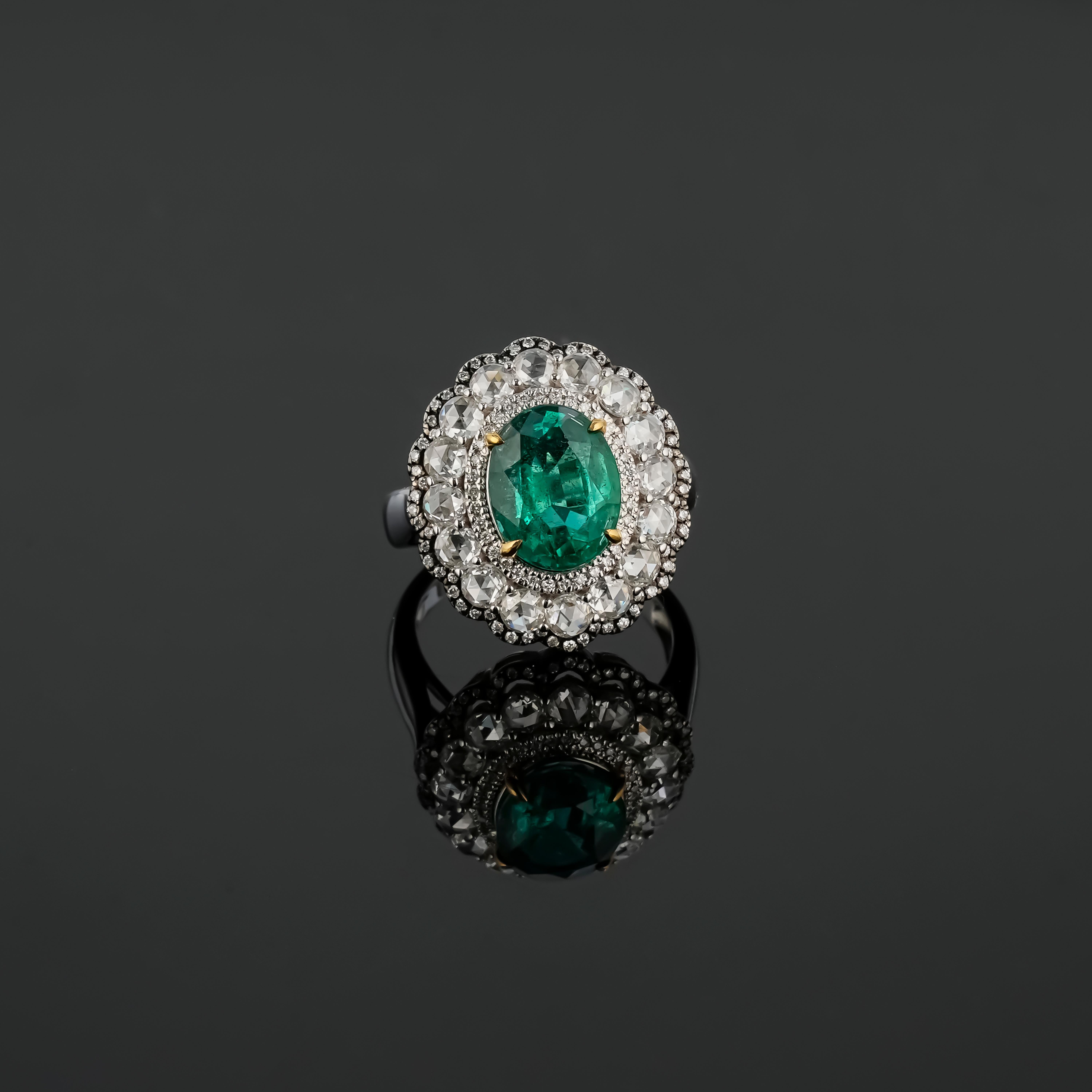 A beautiful, certified 2.70 carat oval shaped Zambian Emerald center stone cocktail ring, adorned with 1.51 carat rose cut and brilliant cut Diamonds. The Emerald Is transparent, with a beautiful vivid green color and amazing luster. Whether worn