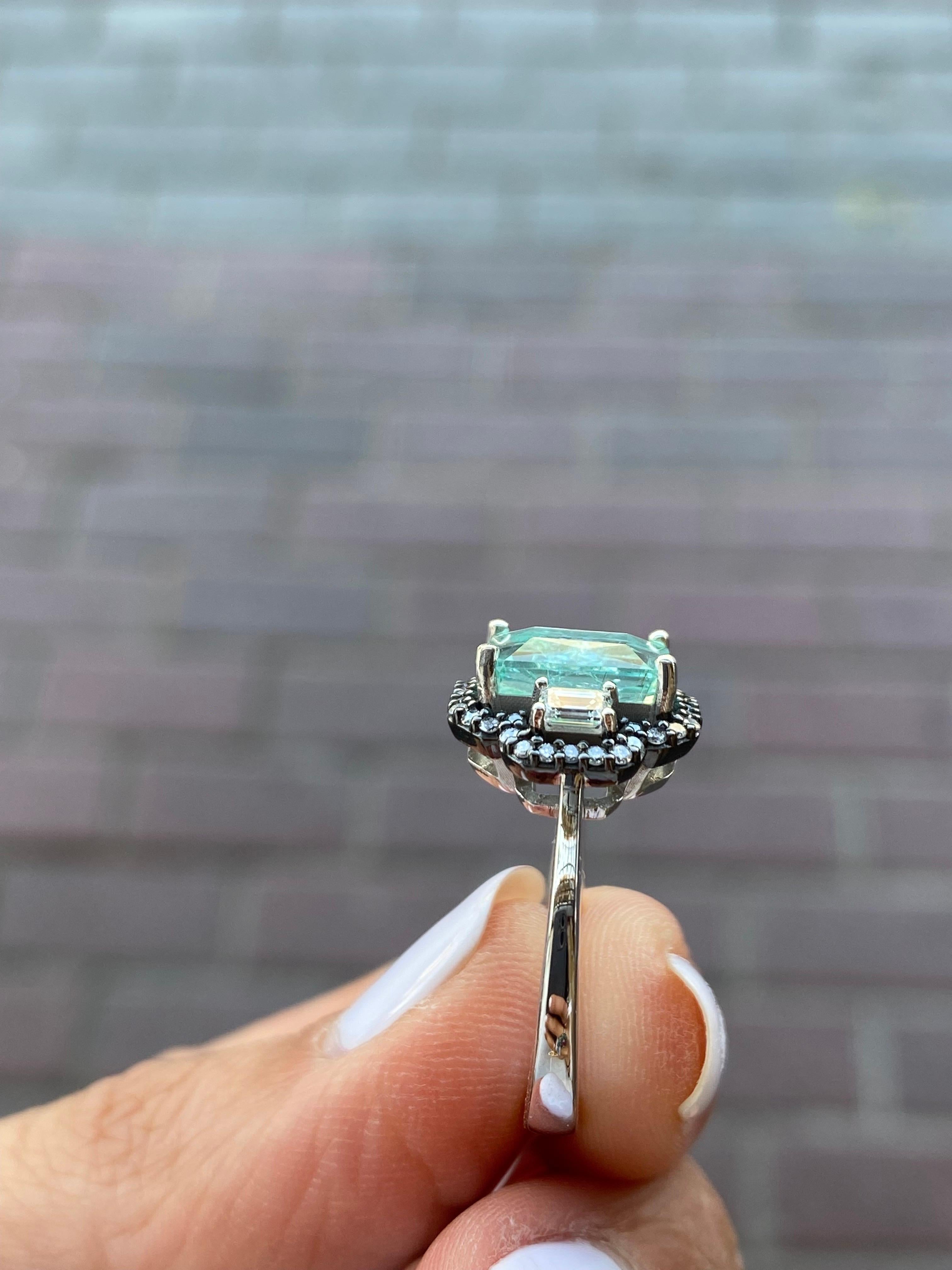 A beautiful combination of 2.71 carat emerald cut Blue Paraiba center stone ring with 0.3 carat VS quality emerald cut Diamond side stones and 0.24 carat brilliant cut Diamond ring, set in solid 18K gold polished in rhodium. The combination of black