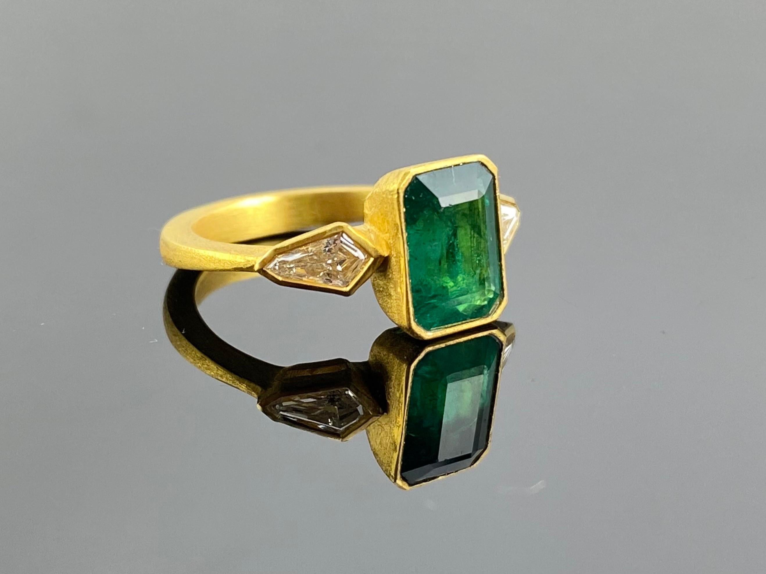 An art-deco looking, natural 2.81 carat Zambian Emerald ring with 0.52 carat kite-shaped VS quality Diamond side stone ring. This is a very unique ring, set in matte finish solid 18K Yellow Gold. The center stone in has a stunning vivid green color,